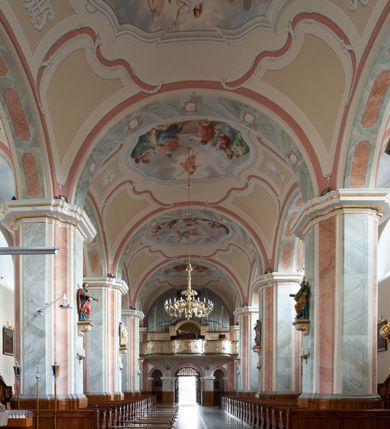 Zdjęcie nr 18: Kościół usytuowany jest w centrum miejscowości na północ od głównej drogi. Na plac kościelny prowadzi główne wejście od strony wschodniej. Świątynia skierowana jest na północ, założona na planie prostokąta z wieżą w fasadzie z prezbiterium zamkniętym trójbocznie, węższym od nawy. Za prezbiterium dobudowana jest kaplica na planie prostokąta, a od zachodu zakrystia. Główne wejście do kościoła znajduje się od strony południowej. 

Wnętrze trójnawowe, halowe, czteroprzęsłowe; nawy oddzielone arkadami na opliastrowanych filarach o wklęsłych narożnikach wspierających sklepienie żaglaste na gurtach. Chór muzyczny wsparty na trzech arkadach filarowych. Balustrada na rzucie wklęsło-wypukłym z uskokami. Wnętrze nawy jest oświetlone przez dziesięć, niskich, zamkniętych półkoliście okien, w prezbiterium cztery analogiczne okna. 

Fasada z ryzalitem w osi środkowej, ujętym zdwojonymi pilastrami, zwieńczonym przerwanym przyczółkiem, na osi portal i balkon z półkoliście zamkniętym oknem. W szczycie fasady drugi przyczółek, w polu monogram maryjny, a poniżej napis: „AVE MARIA GRATIA PLENA DOMINVS TECTVM”. Wyżej na osi czworoboczna wieża, opięta pilastrami w narożach, zwieńczona baniastym hełmem z latarnią. Korpus nawowy o zaokrąglonych narożnikach z podziałami ramowymi i oknami termalnymi. Prezbiterium i kaplica opięte szkarpami. Nad prezbiterium i nawą oddzielne dachy, dwuspadowe. 
