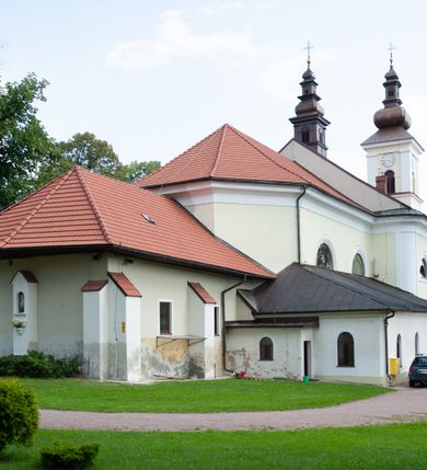 Zdjęcie nr 15: Kościół usytuowany jest w centrum miejscowości na północ od głównej drogi. Na plac kościelny prowadzi główne wejście od strony wschodniej. Świątynia skierowana jest na północ, założona na planie prostokąta z wieżą w fasadzie z prezbiterium zamkniętym trójbocznie, węższym od nawy. Za prezbiterium dobudowana jest kaplica na planie prostokąta, a od zachodu zakrystia. Główne wejście do kościoła znajduje się od strony południowej. 

Wnętrze trójnawowe, halowe, czteroprzęsłowe; nawy oddzielone arkadami na opliastrowanych filarach o wklęsłych narożnikach wspierających sklepienie żaglaste na gurtach. Chór muzyczny wsparty na trzech arkadach filarowych. Balustrada na rzucie wklęsło-wypukłym z uskokami. Wnętrze nawy jest oświetlone przez dziesięć, niskich, zamkniętych półkoliście okien, w prezbiterium cztery analogiczne okna. 

Fasada z ryzalitem w osi środkowej, ujętym zdwojonymi pilastrami, zwieńczonym przerwanym przyczółkiem, na osi portal i balkon z półkoliście zamkniętym oknem. W szczycie fasady drugi przyczółek, w polu monogram maryjny, a poniżej napis: „AVE MARIA GRATIA PLENA DOMINVS TECTVM”. Wyżej na osi czworoboczna wieża, opięta pilastrami w narożach, zwieńczona baniastym hełmem z latarnią. Korpus nawowy o zaokrąglonych narożnikach z podziałami ramowymi i oknami termalnymi. Prezbiterium i kaplica opięte szkarpami. Nad prezbiterium i nawą oddzielne dachy, dwuspadowe. 
