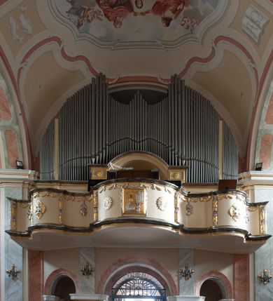 Zdjęcie nr 8: Kościół usytuowany jest w centrum miejscowości na północ od głównej drogi. Na plac kościelny prowadzi główne wejście od strony wschodniej. Świątynia skierowana jest na północ, założona na planie prostokąta z wieżą w fasadzie z prezbiterium zamkniętym trójbocznie, węższym od nawy. Za prezbiterium dobudowana jest kaplica na planie prostokąta, a od zachodu zakrystia. Główne wejście do kościoła znajduje się od strony południowej. 

Wnętrze trójnawowe, halowe, czteroprzęsłowe; nawy oddzielone arkadami na opliastrowanych filarach o wklęsłych narożnikach wspierających sklepienie żaglaste na gurtach. Chór muzyczny wsparty na trzech arkadach filarowych. Balustrada na rzucie wklęsło-wypukłym z uskokami. Wnętrze nawy jest oświetlone przez dziesięć, niskich, zamkniętych półkoliście okien, w prezbiterium cztery analogiczne okna. 

Fasada z ryzalitem w osi środkowej, ujętym zdwojonymi pilastrami, zwieńczonym przerwanym przyczółkiem, na osi portal i balkon z półkoliście zamkniętym oknem. W szczycie fasady drugi przyczółek, w polu monogram maryjny, a poniżej napis: „AVE MARIA GRATIA PLENA DOMINVS TECTVM”. Wyżej na osi czworoboczna wieża, opięta pilastrami w narożach, zwieńczona baniastym hełmem z latarnią. Korpus nawowy o zaokrąglonych narożnikach z podziałami ramowymi i oknami termalnymi. Prezbiterium i kaplica opięte szkarpami. Nad prezbiterium i nawą oddzielne dachy, dwuspadowe. 
