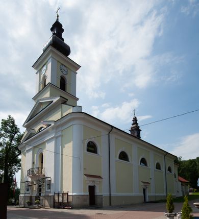 Zdjęcie nr 13: Kościół usytuowany jest w centrum miejscowości na północ od głównej drogi. Na plac kościelny prowadzi główne wejście od strony wschodniej. Świątynia skierowana jest na północ, założona na planie prostokąta z wieżą w fasadzie z prezbiterium zamkniętym trójbocznie, węższym od nawy. Za prezbiterium dobudowana jest kaplica na planie prostokąta, a od zachodu zakrystia. Główne wejście do kościoła znajduje się od strony południowej. 

Wnętrze trójnawowe, halowe, czteroprzęsłowe; nawy oddzielone arkadami na opliastrowanych filarach o wklęsłych narożnikach wspierających sklepienie żaglaste na gurtach. Chór muzyczny wsparty na trzech arkadach filarowych. Balustrada na rzucie wklęsło-wypukłym z uskokami. Wnętrze nawy jest oświetlone przez dziesięć, niskich, zamkniętych półkoliście okien, w prezbiterium cztery analogiczne okna. 

Fasada z ryzalitem w osi środkowej, ujętym zdwojonymi pilastrami, zwieńczonym przerwanym przyczółkiem, na osi portal i balkon z półkoliście zamkniętym oknem. W szczycie fasady drugi przyczółek, w polu monogram maryjny, a poniżej napis: „AVE MARIA GRATIA PLENA DOMINVS TECTVM”. Wyżej na osi czworoboczna wieża, opięta pilastrami w narożach, zwieńczona baniastym hełmem z latarnią. Korpus nawowy o zaokrąglonych narożnikach z podziałami ramowymi i oknami termalnymi. Prezbiterium i kaplica opięte szkarpami. Nad prezbiterium i nawą oddzielne dachy, dwuspadowe. 
