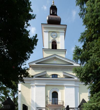 Zdjęcie nr 14: Kościół usytuowany jest w centrum miejscowości na północ od głównej drogi. Na plac kościelny prowadzi główne wejście od strony wschodniej. Świątynia skierowana jest na północ, założona na planie prostokąta z wieżą w fasadzie z prezbiterium zamkniętym trójbocznie, węższym od nawy. Za prezbiterium dobudowana jest kaplica na planie prostokąta, a od zachodu zakrystia. Główne wejście do kościoła znajduje się od strony południowej. 

Wnętrze trójnawowe, halowe, czteroprzęsłowe; nawy oddzielone arkadami na opliastrowanych filarach o wklęsłych narożnikach wspierających sklepienie żaglaste na gurtach. Chór muzyczny wsparty na trzech arkadach filarowych. Balustrada na rzucie wklęsło-wypukłym z uskokami. Wnętrze nawy jest oświetlone przez dziesięć, niskich, zamkniętych półkoliście okien, w prezbiterium cztery analogiczne okna. 

Fasada z ryzalitem w osi środkowej, ujętym zdwojonymi pilastrami, zwieńczonym przerwanym przyczółkiem, na osi portal i balkon z półkoliście zamkniętym oknem. W szczycie fasady drugi przyczółek, w polu monogram maryjny, a poniżej napis: „AVE MARIA GRATIA PLENA DOMINVS TECTVM”. Wyżej na osi czworoboczna wieża, opięta pilastrami w narożach, zwieńczona baniastym hełmem z latarnią. Korpus nawowy o zaokrąglonych narożnikach z podziałami ramowymi i oknami termalnymi. Prezbiterium i kaplica opięte szkarpami. Nad prezbiterium i nawą oddzielne dachy, dwuspadowe. 
