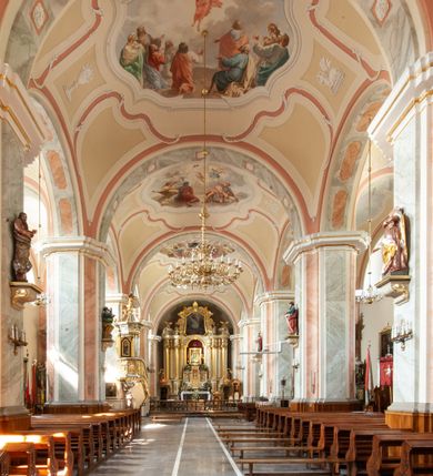 Zdjęcie nr 19: Kościół usytuowany jest w centrum miejscowości na północ od głównej drogi. Na plac kościelny prowadzi główne wejście od strony wschodniej. Świątynia skierowana jest na północ, założona na planie prostokąta z wieżą w fasadzie z prezbiterium zamkniętym trójbocznie, węższym od nawy. Za prezbiterium dobudowana jest kaplica na planie prostokąta, a od zachodu zakrystia. Główne wejście do kościoła znajduje się od strony południowej. 

Wnętrze trójnawowe, halowe, czteroprzęsłowe; nawy oddzielone arkadami na opliastrowanych filarach o wklęsłych narożnikach wspierających sklepienie żaglaste na gurtach. Chór muzyczny wsparty na trzech arkadach filarowych. Balustrada na rzucie wklęsło-wypukłym z uskokami. Wnętrze nawy jest oświetlone przez dziesięć, niskich, zamkniętych półkoliście okien, w prezbiterium cztery analogiczne okna. 

Fasada z ryzalitem w osi środkowej, ujętym zdwojonymi pilastrami, zwieńczonym przerwanym przyczółkiem, na osi portal i balkon z półkoliście zamkniętym oknem. W szczycie fasady drugi przyczółek, w polu monogram maryjny, a poniżej napis: „AVE MARIA GRATIA PLENA DOMINVS TECTVM”. Wyżej na osi czworoboczna wieża, opięta pilastrami w narożach, zwieńczona baniastym hełmem z latarnią. Korpus nawowy o zaokrąglonych narożnikach z podziałami ramowymi i oknami termalnymi. Prezbiterium i kaplica opięte szkarpami. Nad prezbiterium i nawą oddzielne dachy, dwuspadowe. 
