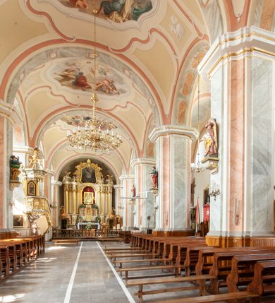 Zdjęcie nr 4: Kościół usytuowany jest w centrum miejscowości na północ od głównej drogi. Na plac kościelny prowadzi główne wejście od strony wschodniej. Świątynia skierowana jest na północ, założona na planie prostokąta z wieżą w fasadzie z prezbiterium zamkniętym trójbocznie, węższym od nawy. Za prezbiterium dobudowana jest kaplica na planie prostokąta, a od zachodu zakrystia. Główne wejście do kościoła znajduje się od strony południowej. 

Wnętrze trójnawowe, halowe, czteroprzęsłowe; nawy oddzielone arkadami na opliastrowanych filarach o wklęsłych narożnikach wspierających sklepienie żaglaste na gurtach. Chór muzyczny wsparty na trzech arkadach filarowych. Balustrada na rzucie wklęsło-wypukłym z uskokami. Wnętrze nawy jest oświetlone przez dziesięć, niskich, zamkniętych półkoliście okien, w prezbiterium cztery analogiczne okna. 

Fasada z ryzalitem w osi środkowej, ujętym zdwojonymi pilastrami, zwieńczonym przerwanym przyczółkiem, na osi portal i balkon z półkoliście zamkniętym oknem. W szczycie fasady drugi przyczółek, w polu monogram maryjny, a poniżej napis: „AVE MARIA GRATIA PLENA DOMINVS TECTVM”. Wyżej na osi czworoboczna wieża, opięta pilastrami w narożach, zwieńczona baniastym hełmem z latarnią. Korpus nawowy o zaokrąglonych narożnikach z podziałami ramowymi i oknami termalnymi. Prezbiterium i kaplica opięte szkarpami. Nad prezbiterium i nawą oddzielne dachy, dwuspadowe. 
