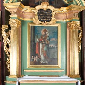 Zdjęcie nr 1: Ołtarz prostopadłościenny, górą wybrzuszony, z ukośnie dostawionymi cokołami, na których kanelowane wolnostojące filary z kompozytowymi kapitelami podtrzymujące wyłamane belkowanie z przerwanym przyczółkiem. Zwieńczenie z lekko wklęsłymi bokami ze spływami wolutowymi zakończone stykającymi się ze sobą wolutami. W partii belkowania kartusz ujęty karbowanymi wstęgami regencyjnymi, wolutami z listkami akantu i zwieńczony muszlą palmetową, w nim napis białą farbą na czarnym tle: „NA PUSZCZY PRZEZ / 7 LAT OD KRUKA / KARMIONY. CUDAMI / SŁYNĄCY. PONIÓSŁ / ŚMIERĆ MĘCZEŃSKĄ / W ANTJOCHJI R. 303”.