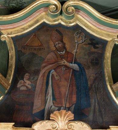 Zdjęcie nr 1: Obraz w zwieńczeniu ołtarza bocznego ma kształt stojącego prostokąta o wklęsłych bokach, ściętych narożach dolnych, zamkniętego łukiem o czterech wklęsłościach. Zawiera całopostaciowy wizerunek św. Erazma biskupa i męczennika. Święty ukazany jest w ujęciu na wprost, z głową zwróconą w trzech czwartych w prawo. Owalną twarz charakteryzują delikatne, sumarycznie opracowane rysy oraz krótki, brązowy, dwudzielny zarost. Święty ubrany jest w strój biskupi, na który składa się alba, czerwona dalmatyka i kapa z niebieską podszewką. Na głowie ma pomarańczową infułę, na piersiach pektorał. Dłonie osłaniają żółte rękawiczki z wyhaftowanymi krzyżykami. Wspartą na piersiach lewą ręką podtrzymuje pastorał, prawa, lekko zgięta w łokciu, opuszczona jest wzdłuż ciała. Głowę świętego okala promienisty nimb. Po lewej stronie kompozycji, obok św. Erazma stoi chrzcielnica, a tuż za nią anioł ze złożonymi na piersiach rękami, z gałązką palmową w dłoni. Postaci znajdują się na pokładzie statku. Po prawej stronie widoczne są narzędzia męczeństwa św. Erazma – dwie pałki, kajdany oraz kołowrót. W górnej partii obrazu po prawej stronie widoczny jest przelatujący kruk mający w dziobie chleb, po lewej trójkąt Trójcy Świętej z trzema płomieniami w narożach i napisem u dołu „FIET UT PETISTI”.  

