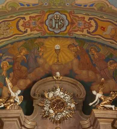 Zdjęcie nr 26: Polichromia pokrywa zarówno powierzchnię ścian, jak i sklepień kościoła, jednak zdecydowanie bardziej dekoracyjne motywy pojawiają się w górnych partiach murów. Dominuje stylizowana ornamentyka roślinna na błękitnym tle, utrzymana w jasnych, żywych tonacjach zróżnicowanych kolorów. Szerokie bordiury o tworzących je fantazyjnych formach i roślinności ujmują niewielkich rozmiarów sceny figuralne umiejscowione pośrodku sklepienia każdego z przęseł kościoła. Kompozycje, o zbliżonych do owalu kształtach przedstawiają: Śmierć św. Józefa w ostatnim przęśle nawy, Ukoronowanie Matki Boskiej na przecięciu nawy z transeptem oraz Wniebowzięcie Najświętszej Marii Panny w przęśle prezbiterium. W konsze absydy ukazana jest scena adoracji kielicha eucharystycznego przez anioły o tęczowych skrzydłach, ubrane w barwne, wzorzyste szaty. Po lewej stronie kościoła, na ścianie transeptu jest ukazana na tle pejzażu scena Chrztu Jezusa. 