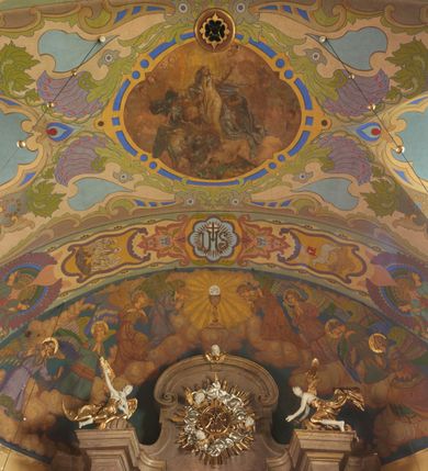 Zdjęcie nr 30: Polichromia pokrywa zarówno powierzchnię ścian, jak i sklepień kościoła, jednak zdecydowanie bardziej dekoracyjne motywy pojawiają się w górnych partiach murów. Dominuje stylizowana ornamentyka roślinna na błękitnym tle, utrzymana w jasnych, żywych tonacjach zróżnicowanych kolorów. Szerokie bordiury o tworzących je fantazyjnych formach i roślinności ujmują niewielkich rozmiarów sceny figuralne umiejscowione pośrodku sklepienia każdego z przęseł kościoła. Kompozycje, o zbliżonych do owalu kształtach przedstawiają: Śmierć św. Józefa w ostatnim przęśle nawy, Ukoronowanie Matki Boskiej na przecięciu nawy z transeptem oraz Wniebowzięcie Najświętszej Marii Panny w przęśle prezbiterium. W konsze absydy ukazana jest scena adoracji kielicha eucharystycznego przez anioły o tęczowych skrzydłach, ubrane w barwne, wzorzyste szaty. Po lewej stronie kościoła, na ścianie transeptu jest ukazana na tle pejzażu scena Chrztu Jezusa. 