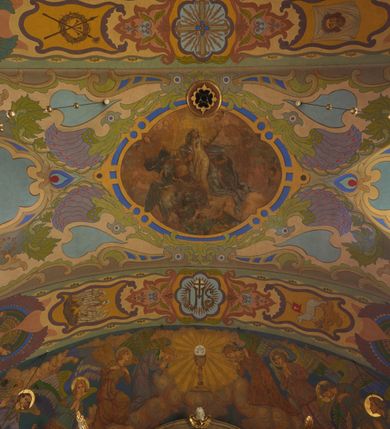 Zdjęcie nr 29: Polichromia pokrywa zarówno powierzchnię ścian, jak i sklepień kościoła, jednak zdecydowanie bardziej dekoracyjne motywy pojawiają się w górnych partiach murów. Dominuje stylizowana ornamentyka roślinna na błękitnym tle, utrzymana w jasnych, żywych tonacjach zróżnicowanych kolorów. Szerokie bordiury o tworzących je fantazyjnych formach i roślinności ujmują niewielkich rozmiarów sceny figuralne umiejscowione pośrodku sklepienia każdego z przęseł kościoła. Kompozycje, o zbliżonych do owalu kształtach przedstawiają: Śmierć św. Józefa w ostatnim przęśle nawy, Ukoronowanie Matki Boskiej na przecięciu nawy z transeptem oraz Wniebowzięcie Najświętszej Marii Panny w przęśle prezbiterium. W konsze absydy ukazana jest scena adoracji kielicha eucharystycznego przez anioły o tęczowych skrzydłach, ubrane w barwne, wzorzyste szaty. Po lewej stronie kościoła, na ścianie transeptu jest ukazana na tle pejzażu scena Chrztu Jezusa. 