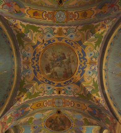 Zdjęcie nr 35: Polichromia pokrywa zarówno powierzchnię ścian, jak i sklepień kościoła, jednak zdecydowanie bardziej dekoracyjne motywy pojawiają się w górnych partiach murów. Dominuje stylizowana ornamentyka roślinna na błękitnym tle, utrzymana w jasnych, żywych tonacjach zróżnicowanych kolorów. Szerokie bordiury o tworzących je fantazyjnych formach i roślinności ujmują niewielkich rozmiarów sceny figuralne umiejscowione pośrodku sklepienia każdego z przęseł kościoła. Kompozycje, o zbliżonych do owalu kształtach przedstawiają: Śmierć św. Józefa w ostatnim przęśle nawy, Ukoronowanie Matki Boskiej na przecięciu nawy z transeptem oraz Wniebowzięcie Najświętszej Marii Panny w przęśle prezbiterium. W konsze absydy ukazana jest scena adoracji kielicha eucharystycznego przez anioły o tęczowych skrzydłach, ubrane w barwne, wzorzyste szaty. Po lewej stronie kościoła, na ścianie transeptu jest ukazana na tle pejzażu scena Chrztu Jezusa. 