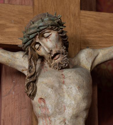 Zdjęcie nr 10: Rzeźba ścięta z tyłu, przybita do krzyża trzema gwoździami, w typie Christo vivo. Ciało w lekkim zwisie o horyzontalnie rozłożonych ramionach, głowa opada na prawy bark, nogi lekko ugięte, stopy skrzyżowane w układzie prawa na lewą. Ciało jest silnie wysmuklone, z wyraźnie rozbudowaną i wypchniętą do przodu klatką piersiową, z podkreślonymi żebrami i zapadłym brzuchem; ręce i nogi są bardzo wychudzone z wyłamanymi barkami, podkreślonymi łokciami i kolanami. Twarz jest pociągła, wychudzona, z głęboko osadzonymi i rzeźbionymi, półotwartymi oczami, wąskim, długim nosem oraz otwartymi ustami z opadającą żuchwą; okolona krótką brodą, głęboko rzeźbioną w regularne pukle oraz długimi włosami ułożonymi w pojedyncze lekko skręcone pukle opadające na plecy oraz na klatkę piersiową. Głowę wieńczy masywna korona cierniowa. Perizonium jest krótkie, silnie opasujące ciało, zawiązane w partii podbrzusza z rozwianym ekspresyjnie fragmentem tkaniny w charakterystycznym odwinięciu na prawym boku. Figura jest polichromowana naturalistycznie, ciało wyróżnia się bladą karnacją z zaznaczonymi śladami męki; perizonium jest złocone i niebieskie na podszewce.
