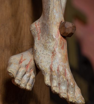 Zdjęcie nr 5: Rzeźba ścięta z tyłu, przybita do krzyża trzema gwoździami, w typie Christo vivo. Ciało w lekkim zwisie o horyzontalnie rozłożonych ramionach, głowa opada na prawy bark, nogi lekko ugięte, stopy skrzyżowane w układzie prawa na lewą. Ciało jest silnie wysmuklone, z wyraźnie rozbudowaną i wypchniętą do przodu klatką piersiową, z podkreślonymi żebrami i zapadłym brzuchem; ręce i nogi są bardzo wychudzone z wyłamanymi barkami, podkreślonymi łokciami i kolanami. Twarz jest pociągła, wychudzona, z głęboko osadzonymi i rzeźbionymi, półotwartymi oczami, wąskim, długim nosem oraz otwartymi ustami z opadającą żuchwą; okolona krótką brodą, głęboko rzeźbioną w regularne pukle oraz długimi włosami ułożonymi w pojedyncze lekko skręcone pukle opadające na plecy oraz na klatkę piersiową. Głowę wieńczy masywna korona cierniowa. Perizonium jest krótkie, silnie opasujące ciało, zawiązane w partii podbrzusza z rozwianym ekspresyjnie fragmentem tkaniny w charakterystycznym odwinięciu na prawym boku. Figura jest polichromowana naturalistycznie, ciało wyróżnia się bladą karnacją z zaznaczonymi śladami męki; perizonium jest złocone i niebieskie na podszewce.