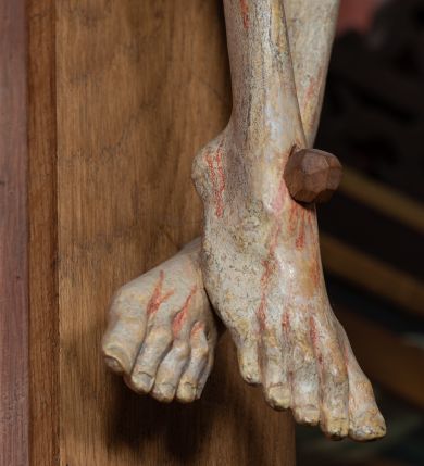 Zdjęcie nr 6: Rzeźba ścięta z tyłu, przybita do krzyża trzema gwoździami, w typie Christo vivo. Ciało w lekkim zwisie o horyzontalnie rozłożonych ramionach, głowa opada na prawy bark, nogi lekko ugięte, stopy skrzyżowane w układzie prawa na lewą. Ciało jest silnie wysmuklone, z wyraźnie rozbudowaną i wypchniętą do przodu klatką piersiową, z podkreślonymi żebrami i zapadłym brzuchem; ręce i nogi są bardzo wychudzone z wyłamanymi barkami, podkreślonymi łokciami i kolanami. Twarz jest pociągła, wychudzona, z głęboko osadzonymi i rzeźbionymi, półotwartymi oczami, wąskim, długim nosem oraz otwartymi ustami z opadającą żuchwą; okolona krótką brodą, głęboko rzeźbioną w regularne pukle oraz długimi włosami ułożonymi w pojedyncze lekko skręcone pukle opadające na plecy oraz na klatkę piersiową. Głowę wieńczy masywna korona cierniowa. Perizonium jest krótkie, silnie opasujące ciało, zawiązane w partii podbrzusza z rozwianym ekspresyjnie fragmentem tkaniny w charakterystycznym odwinięciu na prawym boku. Figura jest polichromowana naturalistycznie, ciało wyróżnia się bladą karnacją z zaznaczonymi śladami męki; perizonium jest złocone i niebieskie na podszewce.