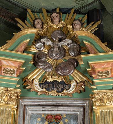 Zdjęcie nr 3: Ołtarz drewniany, ustawiony na jednostopniowej podstawie, jednokondygnacyjny, jednoosiowy ze zwieńczeniem. Ołtarz sarkofagowy z drewnianą mensą i marmurowym portatylem. Antepedium marmoryzowane, z prostokątnym polem z kartuszem i monogramem Marii.

Część środkowa nastawy ujęta parą zdwojonych filarów skierowanych do wewnątrz o kanelowanych trzonach i korynckich kapitelach, podtrzymujących zdwojone imposty i przerwany, wolutowy przyczółek. W polu wnęka w formie stojącego prostokąta z profilowaną ramą, wewnątrz obraz Matki Boskiej Śnieżnej ujęty drugą ramą; nad nim kartusz z napisem „Św(ięta) / MARIO MÓDL SIĘ / ZA NAMI”. W polu zwieńczenia, pomiędzy impostami gołębica Ducha Świętego w otoku z obłoków i glorii promienistej, nad nią trzy uskrzydlone główki anielskie. Ołtarz ujęty wąskimi gablotami na wota. Struktura polichromowana na zielono, z detalami marmoryzowanymi w kolorze jasnobrązowo-beżowym oraz złoconymi filarami, profilami i ornamentyką.