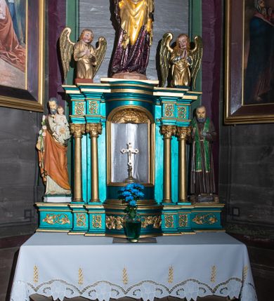 Zdjęcie nr 1: Obraz w kształcie stojącego prostokąta zamkniętego łukiem półkolistym ujęty jest drewnianą, profilowaną i częściowo złoconą ramą. W centrum wielofiguralnej kompozycji stoi, ustawiony frontalnie Jezus ubrany w białą suknię i ciemnoczerwony płaszcz. Prawą rękę unosi w geście błogosławieństwa, lewą trzyma wyciągniętą ponad głową św. Piotra klęczącego z prawej strony kompozycji. Apostoł, pochylając się, zwrócony jest profilem w lewo, w lewej ręce trzyma długą laskę pasterską. Z lewej strony przyklęka św. Jan Ewangelista. Nieco dalej, po obydwu stronach Jezusa ukazani są pozostali apostołowie, wśród których, po lewej stronie kompozycji wyróżnia się św. Jakub Starszy z kijem pielgrzymim z bukłakiem. W tle widoczne jest pokryte obłokami niebo. Kolorystyka jest jasna, pastelowa o szerokiej gamie barwnej. 