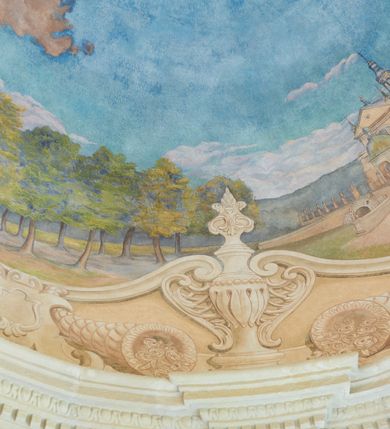 Zdjęcie nr 3: Polichromia umieszczona na półeliptycznej kopule nad kruchtą północną. Przedstawienie ujęte dekoracyjną ramą o fantazyjnym wykroju zdobioną klasycystycznymi wazonami, kartuszami i rogami obfitości. W dolnej części na jasnoczerwonej chmurze ukazane przedstawienie Zaśnięcia Najświętszej Marii Panny. Matka Boska wyobrażona w pozycji leżącej na prześcieradle unoszonym przez grupę aniołów. Maria leży z głową z lewej strony kompozycji z rękami złożonymi na piersi i z ugiętymi w kolanach nogami. Jest ubrana w jasnoróżową suknię, biały welon na głowie oraz niebieski płaszcz ułożony na jej nogach. Aniołowie są ubrani w różnokolorowe tuniki i płaszcze, mają też różne kolory skrzydeł. Przedstawienie okalają uskrzydlone główki aniołków oraz trójka półnagich putt sypiących kwiatki. W górnej części polichromii znajduje się odwrócony pejzaż z przedstawieniem kościoła w Brodach. W centrum jasnobłękitne niebo, a dookoła zielony pejzaż z drzewami. 