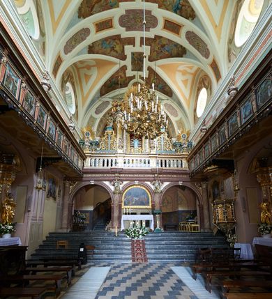 Zdjęcie nr 40: Kościół należy do zespołu dróżek Matki Boskiej, położnych w obrębie klasztoru w Kalwarii Zebrzydowskiej. Świątynia jest położna w centrum wsi, na wschód od głównej drogi, na placu otoczonym kamiennym murem z żeliwnym płotem, który od frontu ozdobiony jest figurami 12 apostołów, umieszczonymi na wysokich cokołach. Główne wejście na plac prowadzi przez bramę od zachodu, flankowaną dwoma filarami, na których ustawione są klasycystyczne wazony. Drugie wejście usytuowane jest od wschodu przez murowaną bramę, nakrytą daszkiem dwuspadowym, na którym ustawiona jest figura grającego na trąbie anioła. Trzecie wejście znajduje się od północy.

Kościół jest budowlą orientowaną, założoną na planie prostokąta, jednonawową, zamkniętą półkolistą absydą. Od zachodu przylega kruchta na planie prostokąta, zamkniętego z jednej strony półkoliście. Wewnątrz kościół dwupiętrowy. Na parterze część wschodnia świątyni podniesiona jest o siedem stopni, oddzielona od nawy trzema półkolistymi arkadami, wspartymi na czterech filarach i ustawionymi przed nimi półkolumnami, które wspierają pełne belkowanie, wyłamane na osiach. W przyłuczach płskorzeźbione główki aniołków. Na fryzie złocony napis: „EIA ADVOCATA NOSTRA OCVLOS MISERICORDES AD NOS CONVERTE ET IESVM BENEDICTV FRCTVM NOBIS OSTENDE”. Za środkową arkadą usytuowana jest niewielka, najstarsza część świątyni – Grób Matki Boskiej, na rzucie prostokąta, sklepiony krzyżowo. W ścianach bocznych nawy są półkoliście zamknięte wnęki na ołtarze. Od zachodu chór muzyczny wsparty jest na trzech arkadach filarowych. Wnętrze obiega drewniany ganek wsparty na metalowych wspornikach, a w części wschodniej i zachodniej na trzech murowanych arkadach. Podniebienie ganku zdobione jest geometrycznym stiukiem. W części nawowej świątyni znajduje się sklepienie kolebkowe z lunetami, w apsydzie hemisferyczne. Wnętrze doświetlone jest sześcioma małymi, okrągłymi oknami znajdującymi się na piętrze od strony północnej i południowej.

Fasada w dolnej części zaakcentowana jest przez monumentalną kruchtę w formie aediculi, założoną na rzucie prostokąta zamkniętego półkoliście. Ściany artykułowane są pięcioma półkolistymi arkadami, wspartymi na filarkach. Od zewnątrz osie ujęte są przez kanelowane kolumny, ustawione na wysokich cokołach, na tle pilastrów. Podpory wznoszą pełne belkowanie i wysunięty gzyms zdobiony kimationem i dekoracją kostkową. Nakrycie w formie kopuły półkolistej z latarnią. Belkowanie ozdobione jest dekoracją roślinną i główkami aniołków. Po bokach kruchty wysunięte są fragmenty muru oporowego do połowy wysokości fasady. Powyżej fasada flankowana przez dwie pary pilastrów z jońskimi kapitelami wspierającymi niepełne belkowanie. Pośrodku duże, półkoliste okno z metalową, dekoracyjną kratą. Szczyt trójkątny z oculusem pośrodku. Na szczycie ustawiona jest figura Najświętszej Marii Panny. Świątynia dookoła obwiedziona szerokim murem oporowym, nakrytym daszkiem, o ukośnych ścianach, flankowanych szkarpami, po sześć na każdej ścianie bocznej i dwoma na ścianie zachodniej oraz wschodniej. Powyżej elewacje ujęte pilastrami z kapitelami jońskimi wznoszącymi niepełne belkowanie. Na wschodniej ścianie półkolista apsyda, nakryta półkopułą. Kościół nakryty dachem siodłowym ze zdwojoną, wysoką latarnią pośrodku. Na narożach dachu ustawione wysokie obeliski na cokołach. 

 