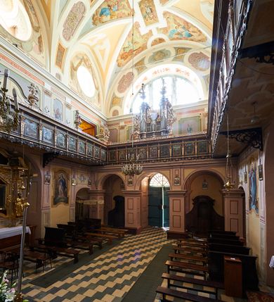 Zdjęcie nr 47: Kościół należy do zespołu dróżek Matki Boskiej, położnych w obrębie klasztoru w Kalwarii Zebrzydowskiej. Świątynia jest położna w centrum wsi, na wschód od głównej drogi, na placu otoczonym kamiennym murem z żeliwnym płotem, który od frontu ozdobiony jest figurami 12 apostołów, umieszczonymi na wysokich cokołach. Główne wejście na plac prowadzi przez bramę od zachodu, flankowaną dwoma filarami, na których ustawione są klasycystyczne wazony. Drugie wejście usytuowane jest od wschodu przez murowaną bramę, nakrytą daszkiem dwuspadowym, na którym ustawiona jest figura grającego na trąbie anioła. Trzecie wejście znajduje się od północy.

Kościół jest budowlą orientowaną, założoną na planie prostokąta, jednonawową, zamkniętą półkolistą absydą. Od zachodu przylega kruchta na planie prostokąta, zamkniętego z jednej strony półkoliście. Wewnątrz kościół dwupiętrowy. Na parterze część wschodnia świątyni podniesiona jest o siedem stopni, oddzielona od nawy trzema półkolistymi arkadami, wspartymi na czterech filarach i ustawionymi przed nimi półkolumnami, które wspierają pełne belkowanie, wyłamane na osiach. W przyłuczach płskorzeźbione główki aniołków. Na fryzie złocony napis: „EIA ADVOCATA NOSTRA OCVLOS MISERICORDES AD NOS CONVERTE ET IESVM BENEDICTV FRCTVM NOBIS OSTENDE”. Za środkową arkadą usytuowana jest niewielka, najstarsza część świątyni – Grób Matki Boskiej, na rzucie prostokąta, sklepiony krzyżowo. W ścianach bocznych nawy są półkoliście zamknięte wnęki na ołtarze. Od zachodu chór muzyczny wsparty jest na trzech arkadach filarowych. Wnętrze obiega drewniany ganek wsparty na metalowych wspornikach, a w części wschodniej i zachodniej na trzech murowanych arkadach. Podniebienie ganku zdobione jest geometrycznym stiukiem. W części nawowej świątyni znajduje się sklepienie kolebkowe z lunetami, w apsydzie hemisferyczne. Wnętrze doświetlone jest sześcioma małymi, okrągłymi oknami znajdującymi się na piętrze od strony północnej i południowej.

Fasada w dolnej części zaakcentowana jest przez monumentalną kruchtę w formie aediculi, założoną na rzucie prostokąta zamkniętego półkoliście. Ściany artykułowane są pięcioma półkolistymi arkadami, wspartymi na filarkach. Od zewnątrz osie ujęte są przez kanelowane kolumny, ustawione na wysokich cokołach, na tle pilastrów. Podpory wznoszą pełne belkowanie i wysunięty gzyms zdobiony kimationem i dekoracją kostkową. Nakrycie w formie kopuły półkolistej z latarnią. Belkowanie ozdobione jest dekoracją roślinną i główkami aniołków. Po bokach kruchty wysunięte są fragmenty muru oporowego do połowy wysokości fasady. Powyżej fasada flankowana przez dwie pary pilastrów z jońskimi kapitelami wspierającymi niepełne belkowanie. Pośrodku duże, półkoliste okno z metalową, dekoracyjną kratą. Szczyt trójkątny z oculusem pośrodku. Na szczycie ustawiona jest figura Najświętszej Marii Panny. Świątynia dookoła obwiedziona szerokim murem oporowym, nakrytym daszkiem, o ukośnych ścianach, flankowanych szkarpami, po sześć na każdej ścianie bocznej i dwoma na ścianie zachodniej oraz wschodniej. Powyżej elewacje ujęte pilastrami z kapitelami jońskimi wznoszącymi niepełne belkowanie. Na wschodniej ścianie półkolista apsyda, nakryta półkopułą. Kościół nakryty dachem siodłowym ze zdwojoną, wysoką latarnią pośrodku. Na narożach dachu ustawione wysokie obeliski na cokołach. 

 