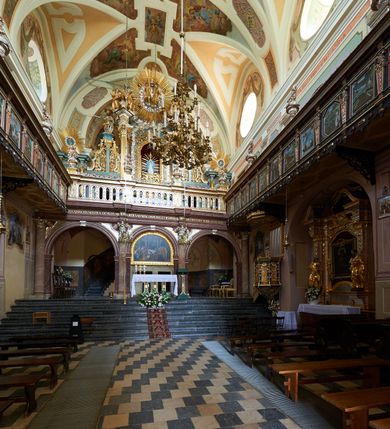 Zdjęcie nr 42: Kościół należy do zespołu dróżek Matki Boskiej, położnych w obrębie klasztoru w Kalwarii Zebrzydowskiej. Świątynia jest położna w centrum wsi, na wschód od głównej drogi, na placu otoczonym kamiennym murem z żeliwnym płotem, który od frontu ozdobiony jest figurami 12 apostołów, umieszczonymi na wysokich cokołach. Główne wejście na plac prowadzi przez bramę od zachodu, flankowaną dwoma filarami, na których ustawione są klasycystyczne wazony. Drugie wejście usytuowane jest od wschodu przez murowaną bramę, nakrytą daszkiem dwuspadowym, na którym ustawiona jest figura grającego na trąbie anioła. Trzecie wejście znajduje się od północy.

Kościół jest budowlą orientowaną, założoną na planie prostokąta, jednonawową, zamkniętą półkolistą absydą. Od zachodu przylega kruchta na planie prostokąta, zamkniętego z jednej strony półkoliście. Wewnątrz kościół dwupiętrowy. Na parterze część wschodnia świątyni podniesiona jest o siedem stopni, oddzielona od nawy trzema półkolistymi arkadami, wspartymi na czterech filarach i ustawionymi przed nimi półkolumnami, które wspierają pełne belkowanie, wyłamane na osiach. W przyłuczach płskorzeźbione główki aniołków. Na fryzie złocony napis: „EIA ADVOCATA NOSTRA OCVLOS MISERICORDES AD NOS CONVERTE ET IESVM BENEDICTV FRCTVM NOBIS OSTENDE”. Za środkową arkadą usytuowana jest niewielka, najstarsza część świątyni – Grób Matki Boskiej, na rzucie prostokąta, sklepiony krzyżowo. W ścianach bocznych nawy są półkoliście zamknięte wnęki na ołtarze. Od zachodu chór muzyczny wsparty jest na trzech arkadach filarowych. Wnętrze obiega drewniany ganek wsparty na metalowych wspornikach, a w części wschodniej i zachodniej na trzech murowanych arkadach. Podniebienie ganku zdobione jest geometrycznym stiukiem. W części nawowej świątyni znajduje się sklepienie kolebkowe z lunetami, w apsydzie hemisferyczne. Wnętrze doświetlone jest sześcioma małymi, okrągłymi oknami znajdującymi się na piętrze od strony północnej i południowej.

Fasada w dolnej części zaakcentowana jest przez monumentalną kruchtę w formie aediculi, założoną na rzucie prostokąta zamkniętego półkoliście. Ściany artykułowane są pięcioma półkolistymi arkadami, wspartymi na filarkach. Od zewnątrz osie ujęte są przez kanelowane kolumny, ustawione na wysokich cokołach, na tle pilastrów. Podpory wznoszą pełne belkowanie i wysunięty gzyms zdobiony kimationem i dekoracją kostkową. Nakrycie w formie kopuły półkolistej z latarnią. Belkowanie ozdobione jest dekoracją roślinną i główkami aniołków. Po bokach kruchty wysunięte są fragmenty muru oporowego do połowy wysokości fasady. Powyżej fasada flankowana przez dwie pary pilastrów z jońskimi kapitelami wspierającymi niepełne belkowanie. Pośrodku duże, półkoliste okno z metalową, dekoracyjną kratą. Szczyt trójkątny z oculusem pośrodku. Na szczycie ustawiona jest figura Najświętszej Marii Panny. Świątynia dookoła obwiedziona szerokim murem oporowym, nakrytym daszkiem, o ukośnych ścianach, flankowanych szkarpami, po sześć na każdej ścianie bocznej i dwoma na ścianie zachodniej oraz wschodniej. Powyżej elewacje ujęte pilastrami z kapitelami jońskimi wznoszącymi niepełne belkowanie. Na wschodniej ścianie półkolista apsyda, nakryta półkopułą. Kościół nakryty dachem siodłowym ze zdwojoną, wysoką latarnią pośrodku. Na narożach dachu ustawione wysokie obeliski na cokołach. 

 