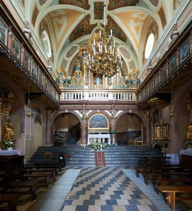 Zdjęcie nr 43: Kościół należy do zespołu dróżek Matki Boskiej, położnych w obrębie klasztoru w Kalwarii Zebrzydowskiej. Świątynia jest położna w centrum wsi, na wschód od głównej drogi, na placu otoczonym kamiennym murem z żeliwnym płotem, który od frontu ozdobiony jest figurami 12 apostołów, umieszczonymi na wysokich cokołach. Główne wejście na plac prowadzi przez bramę od zachodu, flankowaną dwoma filarami, na których ustawione są klasycystyczne wazony. Drugie wejście usytuowane jest od wschodu przez murowaną bramę, nakrytą daszkiem dwuspadowym, na którym ustawiona jest figura grającego na trąbie anioła. Trzecie wejście znajduje się od północy.

Kościół jest budowlą orientowaną, założoną na planie prostokąta, jednonawową, zamkniętą półkolistą absydą. Od zachodu przylega kruchta na planie prostokąta, zamkniętego z jednej strony półkoliście. Wewnątrz kościół dwupiętrowy. Na parterze część wschodnia świątyni podniesiona jest o siedem stopni, oddzielona od nawy trzema półkolistymi arkadami, wspartymi na czterech filarach i ustawionymi przed nimi półkolumnami, które wspierają pełne belkowanie, wyłamane na osiach. W przyłuczach płskorzeźbione główki aniołków. Na fryzie złocony napis: „EIA ADVOCATA NOSTRA OCVLOS MISERICORDES AD NOS CONVERTE ET IESVM BENEDICTV FRCTVM NOBIS OSTENDE”. Za środkową arkadą usytuowana jest niewielka, najstarsza część świątyni – Grób Matki Boskiej, na rzucie prostokąta, sklepiony krzyżowo. W ścianach bocznych nawy są półkoliście zamknięte wnęki na ołtarze. Od zachodu chór muzyczny wsparty jest na trzech arkadach filarowych. Wnętrze obiega drewniany ganek wsparty na metalowych wspornikach, a w części wschodniej i zachodniej na trzech murowanych arkadach. Podniebienie ganku zdobione jest geometrycznym stiukiem. W części nawowej świątyni znajduje się sklepienie kolebkowe z lunetami, w apsydzie hemisferyczne. Wnętrze doświetlone jest sześcioma małymi, okrągłymi oknami znajdującymi się na piętrze od strony północnej i południowej.

Fasada w dolnej części zaakcentowana jest przez monumentalną kruchtę w formie aediculi, założoną na rzucie prostokąta zamkniętego półkoliście. Ściany artykułowane są pięcioma półkolistymi arkadami, wspartymi na filarkach. Od zewnątrz osie ujęte są przez kanelowane kolumny, ustawione na wysokich cokołach, na tle pilastrów. Podpory wznoszą pełne belkowanie i wysunięty gzyms zdobiony kimationem i dekoracją kostkową. Nakrycie w formie kopuły półkolistej z latarnią. Belkowanie ozdobione jest dekoracją roślinną i główkami aniołków. Po bokach kruchty wysunięte są fragmenty muru oporowego do połowy wysokości fasady. Powyżej fasada flankowana przez dwie pary pilastrów z jońskimi kapitelami wspierającymi niepełne belkowanie. Pośrodku duże, półkoliste okno z metalową, dekoracyjną kratą. Szczyt trójkątny z oculusem pośrodku. Na szczycie ustawiona jest figura Najświętszej Marii Panny. Świątynia dookoła obwiedziona szerokim murem oporowym, nakrytym daszkiem, o ukośnych ścianach, flankowanych szkarpami, po sześć na każdej ścianie bocznej i dwoma na ścianie zachodniej oraz wschodniej. Powyżej elewacje ujęte pilastrami z kapitelami jońskimi wznoszącymi niepełne belkowanie. Na wschodniej ścianie półkolista apsyda, nakryta półkopułą. Kościół nakryty dachem siodłowym ze zdwojoną, wysoką latarnią pośrodku. Na narożach dachu ustawione wysokie obeliski na cokołach. 

 