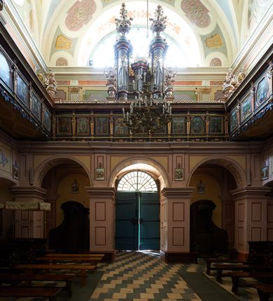Zdjęcie nr 48: Kościół należy do zespołu dróżek Matki Boskiej, położnych w obrębie klasztoru w Kalwarii Zebrzydowskiej. Świątynia jest położna w centrum wsi, na wschód od głównej drogi, na placu otoczonym kamiennym murem z żeliwnym płotem, który od frontu ozdobiony jest figurami 12 apostołów, umieszczonymi na wysokich cokołach. Główne wejście na plac prowadzi przez bramę od zachodu, flankowaną dwoma filarami, na których ustawione są klasycystyczne wazony. Drugie wejście usytuowane jest od wschodu przez murowaną bramę, nakrytą daszkiem dwuspadowym, na którym ustawiona jest figura grającego na trąbie anioła. Trzecie wejście znajduje się od północy.

Kościół jest budowlą orientowaną, założoną na planie prostokąta, jednonawową, zamkniętą półkolistą absydą. Od zachodu przylega kruchta na planie prostokąta, zamkniętego z jednej strony półkoliście. Wewnątrz kościół dwupiętrowy. Na parterze część wschodnia świątyni podniesiona jest o siedem stopni, oddzielona od nawy trzema półkolistymi arkadami, wspartymi na czterech filarach i ustawionymi przed nimi półkolumnami, które wspierają pełne belkowanie, wyłamane na osiach. W przyłuczach płskorzeźbione główki aniołków. Na fryzie złocony napis: „EIA ADVOCATA NOSTRA OCVLOS MISERICORDES AD NOS CONVERTE ET IESVM BENEDICTV FRCTVM NOBIS OSTENDE”. Za środkową arkadą usytuowana jest niewielka, najstarsza część świątyni – Grób Matki Boskiej, na rzucie prostokąta, sklepiony krzyżowo. W ścianach bocznych nawy są półkoliście zamknięte wnęki na ołtarze. Od zachodu chór muzyczny wsparty jest na trzech arkadach filarowych. Wnętrze obiega drewniany ganek wsparty na metalowych wspornikach, a w części wschodniej i zachodniej na trzech murowanych arkadach. Podniebienie ganku zdobione jest geometrycznym stiukiem. W części nawowej świątyni znajduje się sklepienie kolebkowe z lunetami, w apsydzie hemisferyczne. Wnętrze doświetlone jest sześcioma małymi, okrągłymi oknami znajdującymi się na piętrze od strony północnej i południowej.

Fasada w dolnej części zaakcentowana jest przez monumentalną kruchtę w formie aediculi, założoną na rzucie prostokąta zamkniętego półkoliście. Ściany artykułowane są pięcioma półkolistymi arkadami, wspartymi na filarkach. Od zewnątrz osie ujęte są przez kanelowane kolumny, ustawione na wysokich cokołach, na tle pilastrów. Podpory wznoszą pełne belkowanie i wysunięty gzyms zdobiony kimationem i dekoracją kostkową. Nakrycie w formie kopuły półkolistej z latarnią. Belkowanie ozdobione jest dekoracją roślinną i główkami aniołków. Po bokach kruchty wysunięte są fragmenty muru oporowego do połowy wysokości fasady. Powyżej fasada flankowana przez dwie pary pilastrów z jońskimi kapitelami wspierającymi niepełne belkowanie. Pośrodku duże, półkoliste okno z metalową, dekoracyjną kratą. Szczyt trójkątny z oculusem pośrodku. Na szczycie ustawiona jest figura Najświętszej Marii Panny. Świątynia dookoła obwiedziona szerokim murem oporowym, nakrytym daszkiem, o ukośnych ścianach, flankowanych szkarpami, po sześć na każdej ścianie bocznej i dwoma na ścianie zachodniej oraz wschodniej. Powyżej elewacje ujęte pilastrami z kapitelami jońskimi wznoszącymi niepełne belkowanie. Na wschodniej ścianie półkolista apsyda, nakryta półkopułą. Kościół nakryty dachem siodłowym ze zdwojoną, wysoką latarnią pośrodku. Na narożach dachu ustawione wysokie obeliski na cokołach. 

 