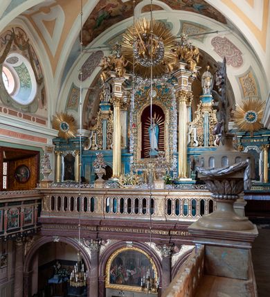 Zdjęcie nr 45: Kościół należy do zespołu dróżek Matki Boskiej, położnych w obrębie klasztoru w Kalwarii Zebrzydowskiej. Świątynia jest położna w centrum wsi, na wschód od głównej drogi, na placu otoczonym kamiennym murem z żeliwnym płotem, który od frontu ozdobiony jest figurami 12 apostołów, umieszczonymi na wysokich cokołach. Główne wejście na plac prowadzi przez bramę od zachodu, flankowaną dwoma filarami, na których ustawione są klasycystyczne wazony. Drugie wejście usytuowane jest od wschodu przez murowaną bramę, nakrytą daszkiem dwuspadowym, na którym ustawiona jest figura grającego na trąbie anioła. Trzecie wejście znajduje się od północy.

Kościół jest budowlą orientowaną, założoną na planie prostokąta, jednonawową, zamkniętą półkolistą absydą. Od zachodu przylega kruchta na planie prostokąta, zamkniętego z jednej strony półkoliście. Wewnątrz kościół dwupiętrowy. Na parterze część wschodnia świątyni podniesiona jest o siedem stopni, oddzielona od nawy trzema półkolistymi arkadami, wspartymi na czterech filarach i ustawionymi przed nimi półkolumnami, które wspierają pełne belkowanie, wyłamane na osiach. W przyłuczach płskorzeźbione główki aniołków. Na fryzie złocony napis: „EIA ADVOCATA NOSTRA OCVLOS MISERICORDES AD NOS CONVERTE ET IESVM BENEDICTV FRCTVM NOBIS OSTENDE”. Za środkową arkadą usytuowana jest niewielka, najstarsza część świątyni – Grób Matki Boskiej, na rzucie prostokąta, sklepiony krzyżowo. W ścianach bocznych nawy są półkoliście zamknięte wnęki na ołtarze. Od zachodu chór muzyczny wsparty jest na trzech arkadach filarowych. Wnętrze obiega drewniany ganek wsparty na metalowych wspornikach, a w części wschodniej i zachodniej na trzech murowanych arkadach. Podniebienie ganku zdobione jest geometrycznym stiukiem. W części nawowej świątyni znajduje się sklepienie kolebkowe z lunetami, w apsydzie hemisferyczne. Wnętrze doświetlone jest sześcioma małymi, okrągłymi oknami znajdującymi się na piętrze od strony północnej i południowej.

Fasada w dolnej części zaakcentowana jest przez monumentalną kruchtę w formie aediculi, założoną na rzucie prostokąta zamkniętego półkoliście. Ściany artykułowane są pięcioma półkolistymi arkadami, wspartymi na filarkach. Od zewnątrz osie ujęte są przez kanelowane kolumny, ustawione na wysokich cokołach, na tle pilastrów. Podpory wznoszą pełne belkowanie i wysunięty gzyms zdobiony kimationem i dekoracją kostkową. Nakrycie w formie kopuły półkolistej z latarnią. Belkowanie ozdobione jest dekoracją roślinną i główkami aniołków. Po bokach kruchty wysunięte są fragmenty muru oporowego do połowy wysokości fasady. Powyżej fasada flankowana przez dwie pary pilastrów z jońskimi kapitelami wspierającymi niepełne belkowanie. Pośrodku duże, półkoliste okno z metalową, dekoracyjną kratą. Szczyt trójkątny z oculusem pośrodku. Na szczycie ustawiona jest figura Najświętszej Marii Panny. Świątynia dookoła obwiedziona szerokim murem oporowym, nakrytym daszkiem, o ukośnych ścianach, flankowanych szkarpami, po sześć na każdej ścianie bocznej i dwoma na ścianie zachodniej oraz wschodniej. Powyżej elewacje ujęte pilastrami z kapitelami jońskimi wznoszącymi niepełne belkowanie. Na wschodniej ścianie półkolista apsyda, nakryta półkopułą. Kościół nakryty dachem siodłowym ze zdwojoną, wysoką latarnią pośrodku. Na narożach dachu ustawione wysokie obeliski na cokołach. 

 