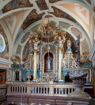 Zdjęcie nr 44: Kościół należy do zespołu dróżek Matki Boskiej, położnych w obrębie klasztoru w Kalwarii Zebrzydowskiej. Świątynia jest położna w centrum wsi, na wschód od głównej drogi, na placu otoczonym kamiennym murem z żeliwnym płotem, który od frontu ozdobiony jest figurami 12 apostołów, umieszczonymi na wysokich cokołach. Główne wejście na plac prowadzi przez bramę od zachodu, flankowaną dwoma filarami, na których ustawione są klasycystyczne wazony. Drugie wejście usytuowane jest od wschodu przez murowaną bramę, nakrytą daszkiem dwuspadowym, na którym ustawiona jest figura grającego na trąbie anioła. Trzecie wejście znajduje się od północy.

Kościół jest budowlą orientowaną, założoną na planie prostokąta, jednonawową, zamkniętą półkolistą absydą. Od zachodu przylega kruchta na planie prostokąta, zamkniętego z jednej strony półkoliście. Wewnątrz kościół dwupiętrowy. Na parterze część wschodnia świątyni podniesiona jest o siedem stopni, oddzielona od nawy trzema półkolistymi arkadami, wspartymi na czterech filarach i ustawionymi przed nimi półkolumnami, które wspierają pełne belkowanie, wyłamane na osiach. W przyłuczach płskorzeźbione główki aniołków. Na fryzie złocony napis: „EIA ADVOCATA NOSTRA OCVLOS MISERICORDES AD NOS CONVERTE ET IESVM BENEDICTV FRCTVM NOBIS OSTENDE”. Za środkową arkadą usytuowana jest niewielka, najstarsza część świątyni – Grób Matki Boskiej, na rzucie prostokąta, sklepiony krzyżowo. W ścianach bocznych nawy są półkoliście zamknięte wnęki na ołtarze. Od zachodu chór muzyczny wsparty jest na trzech arkadach filarowych. Wnętrze obiega drewniany ganek wsparty na metalowych wspornikach, a w części wschodniej i zachodniej na trzech murowanych arkadach. Podniebienie ganku zdobione jest geometrycznym stiukiem. W części nawowej świątyni znajduje się sklepienie kolebkowe z lunetami, w apsydzie hemisferyczne. Wnętrze doświetlone jest sześcioma małymi, okrągłymi oknami znajdującymi się na piętrze od strony północnej i południowej.

Fasada w dolnej części zaakcentowana jest przez monumentalną kruchtę w formie aediculi, założoną na rzucie prostokąta zamkniętego półkoliście. Ściany artykułowane są pięcioma półkolistymi arkadami, wspartymi na filarkach. Od zewnątrz osie ujęte są przez kanelowane kolumny, ustawione na wysokich cokołach, na tle pilastrów. Podpory wznoszą pełne belkowanie i wysunięty gzyms zdobiony kimationem i dekoracją kostkową. Nakrycie w formie kopuły półkolistej z latarnią. Belkowanie ozdobione jest dekoracją roślinną i główkami aniołków. Po bokach kruchty wysunięte są fragmenty muru oporowego do połowy wysokości fasady. Powyżej fasada flankowana przez dwie pary pilastrów z jońskimi kapitelami wspierającymi niepełne belkowanie. Pośrodku duże, półkoliste okno z metalową, dekoracyjną kratą. Szczyt trójkątny z oculusem pośrodku. Na szczycie ustawiona jest figura Najświętszej Marii Panny. Świątynia dookoła obwiedziona szerokim murem oporowym, nakrytym daszkiem, o ukośnych ścianach, flankowanych szkarpami, po sześć na każdej ścianie bocznej i dwoma na ścianie zachodniej oraz wschodniej. Powyżej elewacje ujęte pilastrami z kapitelami jońskimi wznoszącymi niepełne belkowanie. Na wschodniej ścianie półkolista apsyda, nakryta półkopułą. Kościół nakryty dachem siodłowym ze zdwojoną, wysoką latarnią pośrodku. Na narożach dachu ustawione wysokie obeliski na cokołach. 

 