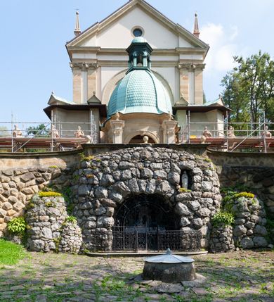 Zdjęcie nr 15: Kościół należy do zespołu dróżek Matki Boskiej, położnych w obrębie klasztoru w Kalwarii Zebrzydowskiej. Świątynia jest położna w centrum wsi, na wschód od głównej drogi, na placu otoczonym kamiennym murem z żeliwnym płotem, który od frontu ozdobiony jest figurami 12 apostołów, umieszczonymi na wysokich cokołach. Główne wejście na plac prowadzi przez bramę od zachodu, flankowaną dwoma filarami, na których ustawione są klasycystyczne wazony. Drugie wejście usytuowane jest od wschodu przez murowaną bramę, nakrytą daszkiem dwuspadowym, na którym ustawiona jest figura grającego na trąbie anioła. Trzecie wejście znajduje się od północy.

Kościół jest budowlą orientowaną, założoną na planie prostokąta, jednonawową, zamkniętą półkolistą absydą. Od zachodu przylega kruchta na planie prostokąta, zamkniętego z jednej strony półkoliście. Wewnątrz kościół dwupiętrowy. Na parterze część wschodnia świątyni podniesiona jest o siedem stopni, oddzielona od nawy trzema półkolistymi arkadami, wspartymi na czterech filarach i ustawionymi przed nimi półkolumnami, które wspierają pełne belkowanie, wyłamane na osiach. W przyłuczach płskorzeźbione główki aniołków. Na fryzie złocony napis: „EIA ADVOCATA NOSTRA OCVLOS MISERICORDES AD NOS CONVERTE ET IESVM BENEDICTV FRCTVM NOBIS OSTENDE”. Za środkową arkadą usytuowana jest niewielka, najstarsza część świątyni – Grób Matki Boskiej, na rzucie prostokąta, sklepiony krzyżowo. W ścianach bocznych nawy są półkoliście zamknięte wnęki na ołtarze. Od zachodu chór muzyczny wsparty jest na trzech arkadach filarowych. Wnętrze obiega drewniany ganek wsparty na metalowych wspornikach, a w części wschodniej i zachodniej na trzech murowanych arkadach. Podniebienie ganku zdobione jest geometrycznym stiukiem. W części nawowej świątyni znajduje się sklepienie kolebkowe z lunetami, w apsydzie hemisferyczne. Wnętrze doświetlone jest sześcioma małymi, okrągłymi oknami znajdującymi się na piętrze od strony północnej i południowej.

Fasada w dolnej części zaakcentowana jest przez monumentalną kruchtę w formie aediculi, założoną na rzucie prostokąta zamkniętego półkoliście. Ściany artykułowane są pięcioma półkolistymi arkadami, wspartymi na filarkach. Od zewnątrz osie ujęte są przez kanelowane kolumny, ustawione na wysokich cokołach, na tle pilastrów. Podpory wznoszą pełne belkowanie i wysunięty gzyms zdobiony kimationem i dekoracją kostkową. Nakrycie w formie kopuły półkolistej z latarnią. Belkowanie ozdobione jest dekoracją roślinną i główkami aniołków. Po bokach kruchty wysunięte są fragmenty muru oporowego do połowy wysokości fasady. Powyżej fasada flankowana przez dwie pary pilastrów z jońskimi kapitelami wspierającymi niepełne belkowanie. Pośrodku duże, półkoliste okno z metalową, dekoracyjną kratą. Szczyt trójkątny z oculusem pośrodku. Na szczycie ustawiona jest figura Najświętszej Marii Panny. Świątynia dookoła obwiedziona szerokim murem oporowym, nakrytym daszkiem, o ukośnych ścianach, flankowanych szkarpami, po sześć na każdej ścianie bocznej i dwoma na ścianie zachodniej oraz wschodniej. Powyżej elewacje ujęte pilastrami z kapitelami jońskimi wznoszącymi niepełne belkowanie. Na wschodniej ścianie półkolista apsyda, nakryta półkopułą. Kościół nakryty dachem siodłowym ze zdwojoną, wysoką latarnią pośrodku. Na narożach dachu ustawione wysokie obeliski na cokołach. 

 