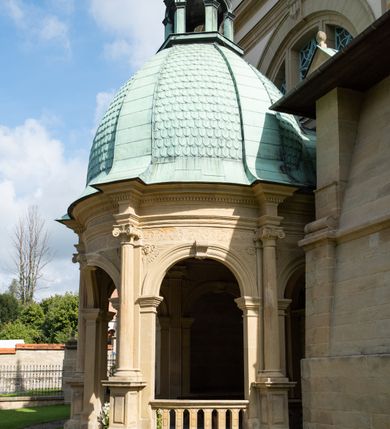 Zdjęcie nr 7: Kościół należy do zespołu dróżek Matki Boskiej, położnych w obrębie klasztoru w Kalwarii Zebrzydowskiej. Świątynia jest położna w centrum wsi, na wschód od głównej drogi, na placu otoczonym kamiennym murem z żeliwnym płotem, który od frontu ozdobiony jest figurami 12 apostołów, umieszczonymi na wysokich cokołach. Główne wejście na plac prowadzi przez bramę od zachodu, flankowaną dwoma filarami, na których ustawione są klasycystyczne wazony. Drugie wejście usytuowane jest od wschodu przez murowaną bramę, nakrytą daszkiem dwuspadowym, na którym ustawiona jest figura grającego na trąbie anioła. Trzecie wejście znajduje się od północy.

Kościół jest budowlą orientowaną, założoną na planie prostokąta, jednonawową, zamkniętą półkolistą absydą. Od zachodu przylega kruchta na planie prostokąta, zamkniętego z jednej strony półkoliście. Wewnątrz kościół dwupiętrowy. Na parterze część wschodnia świątyni podniesiona jest o siedem stopni, oddzielona od nawy trzema półkolistymi arkadami, wspartymi na czterech filarach i ustawionymi przed nimi półkolumnami, które wspierają pełne belkowanie, wyłamane na osiach. W przyłuczach płskorzeźbione główki aniołków. Na fryzie złocony napis: „EIA ADVOCATA NOSTRA OCVLOS MISERICORDES AD NOS CONVERTE ET IESVM BENEDICTV FRCTVM NOBIS OSTENDE”. Za środkową arkadą usytuowana jest niewielka, najstarsza część świątyni – Grób Matki Boskiej, na rzucie prostokąta, sklepiony krzyżowo. W ścianach bocznych nawy są półkoliście zamknięte wnęki na ołtarze. Od zachodu chór muzyczny wsparty jest na trzech arkadach filarowych. Wnętrze obiega drewniany ganek wsparty na metalowych wspornikach, a w części wschodniej i zachodniej na trzech murowanych arkadach. Podniebienie ganku zdobione jest geometrycznym stiukiem. W części nawowej świątyni znajduje się sklepienie kolebkowe z lunetami, w apsydzie hemisferyczne. Wnętrze doświetlone jest sześcioma małymi, okrągłymi oknami znajdującymi się na piętrze od strony północnej i południowej.

Fasada w dolnej części zaakcentowana jest przez monumentalną kruchtę w formie aediculi, założoną na rzucie prostokąta zamkniętego półkoliście. Ściany artykułowane są pięcioma półkolistymi arkadami, wspartymi na filarkach. Od zewnątrz osie ujęte są przez kanelowane kolumny, ustawione na wysokich cokołach, na tle pilastrów. Podpory wznoszą pełne belkowanie i wysunięty gzyms zdobiony kimationem i dekoracją kostkową. Nakrycie w formie kopuły półkolistej z latarnią. Belkowanie ozdobione jest dekoracją roślinną i główkami aniołków. Po bokach kruchty wysunięte są fragmenty muru oporowego do połowy wysokości fasady. Powyżej fasada flankowana przez dwie pary pilastrów z jońskimi kapitelami wspierającymi niepełne belkowanie. Pośrodku duże, półkoliste okno z metalową, dekoracyjną kratą. Szczyt trójkątny z oculusem pośrodku. Na szczycie ustawiona jest figura Najświętszej Marii Panny. Świątynia dookoła obwiedziona szerokim murem oporowym, nakrytym daszkiem, o ukośnych ścianach, flankowanych szkarpami, po sześć na każdej ścianie bocznej i dwoma na ścianie zachodniej oraz wschodniej. Powyżej elewacje ujęte pilastrami z kapitelami jońskimi wznoszącymi niepełne belkowanie. Na wschodniej ścianie półkolista apsyda, nakryta półkopułą. Kościół nakryty dachem siodłowym ze zdwojoną, wysoką latarnią pośrodku. Na narożach dachu ustawione wysokie obeliski na cokołach. 

 