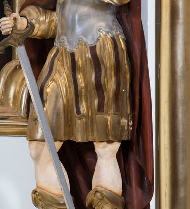 Zdjęcie nr 12: Ołtarz drewniany, prostopadłościenny. Mensa drewniana, sarkofagowa, antepedium zdobione płaskorzeźbionym kartuszem z umieszczonym w polu godłem herbu Uniwersytetu Krakowskiego na czerwonym tle.

 Nastawa architektoniczna, trójosiowa, jednokondygnacyjna ze zwieńczeniem, osadzona na dwustrefowym cokole, o osiach bocznych ustawionych ukośnie. Kondygnacja ujęta parą pilastrów oraz dwiema parami kolumn podtrzymujących przerwane belkowanie,  na którym znajduje się para puttów. W polu środkowym obraz z przedstawieniem Matki Boskiej od Odkupienia Niewolników ujęty prostokątną, profilowaną ramą zamkniętą łukiem nadwieszonym. Na cokole, po bokach obrazu ustawione dwie rzeźby: po lewej św. Kryspina, po prawej św. Kryspiniana; w osiach bocznych, w płytkich wnękach: po lewej rzeźba św. Szczepana, po prawej św. Wawrzyńca. Nad obrazem Matki Boskiej płaskorzeźbiony kartusz rocaille’owy z wpisanym w polu napisem „O / MARYO / odkupicielko / więźniów / módl się / za nami!”.

 Zwieńczenie w formie rozbudowanej aediculi, o osiach bocznych ustawionych ukośnie, z przodu flankowane dwiema wolutami z siedzącą na nich parą aniołków, zamknięte przerywanym, profilowanym gzymsem z ulokowaną na nim parą wazonów płomienistych. W polu zwieńczenia płycina wypełniona obłokami, o fantazyjnym kartuszowym wykroju z przedstawieniem Oka Opatrzności wpisanym w trójkąt na tle trzech wiązek promieni. Szczyt jest w formie promienistej glorii z parą uskrzydlonych główek anielskich.

 Kolumny złocone, ustawione na profilowanych bazach, o gładkim trzonie, kapitele w porządku kompozytowym.

 Partie cokołu zdobione prostokątnymi płycinami o wyciętych narożach.

 Struktura malowana w kolorze jasnobeżowym, ornamentyka i detale złocone i srebrzone, profilowania w kolorze czerwonym i złoconym.