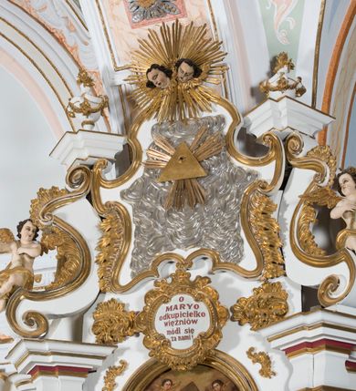 Zdjęcie nr 3: Ołtarz drewniany, prostopadłościenny. Mensa drewniana, sarkofagowa, antepedium zdobione płaskorzeźbionym kartuszem z umieszczonym w polu godłem herbu Uniwersytetu Krakowskiego na czerwonym tle.

 Nastawa architektoniczna, trójosiowa, jednokondygnacyjna ze zwieńczeniem, osadzona na dwustrefowym cokole, o osiach bocznych ustawionych ukośnie. Kondygnacja ujęta parą pilastrów oraz dwiema parami kolumn podtrzymujących przerwane belkowanie,  na którym znajduje się para puttów. W polu środkowym obraz z przedstawieniem Matki Boskiej od Odkupienia Niewolników ujęty prostokątną, profilowaną ramą zamkniętą łukiem nadwieszonym. Na cokole, po bokach obrazu ustawione dwie rzeźby: po lewej św. Kryspina, po prawej św. Kryspiniana; w osiach bocznych, w płytkich wnękach: po lewej rzeźba św. Szczepana, po prawej św. Wawrzyńca. Nad obrazem Matki Boskiej płaskorzeźbiony kartusz rocaille’owy z wpisanym w polu napisem „O / MARYO / odkupicielko / więźniów / módl się / za nami!”.

 Zwieńczenie w formie rozbudowanej aediculi, o osiach bocznych ustawionych ukośnie, z przodu flankowane dwiema wolutami z siedzącą na nich parą aniołków, zamknięte przerywanym, profilowanym gzymsem z ulokowaną na nim parą wazonów płomienistych. W polu zwieńczenia płycina wypełniona obłokami, o fantazyjnym kartuszowym wykroju z przedstawieniem Oka Opatrzności wpisanym w trójkąt na tle trzech wiązek promieni. Szczyt jest w formie promienistej glorii z parą uskrzydlonych główek anielskich.

 Kolumny złocone, ustawione na profilowanych bazach, o gładkim trzonie, kapitele w porządku kompozytowym.

 Partie cokołu zdobione prostokątnymi płycinami o wyciętych narożach.

 Struktura malowana w kolorze jasnobeżowym, ornamentyka i detale złocone i srebrzone, profilowania w kolorze czerwonym i złoconym.