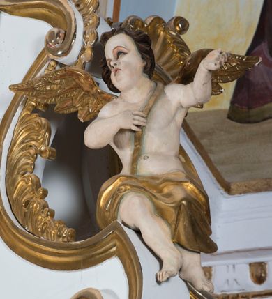 Zdjęcie nr 26: Ołtarz drewniany, prostopadłościenny. Mensa drewniana, sarkofagowa, antepedium zdobione płaskorzeźbionym kartuszem z umieszczonym w polu godłem herbu Uniwersytetu Krakowskiego na czerwonym tle.

 Nastawa architektoniczna, trójosiowa, jednokondygnacyjna ze zwieńczeniem, osadzona na dwustrefowym cokole, o osiach bocznych ustawionych ukośnie. Kondygnacja ujęta parą pilastrów oraz dwiema parami kolumn podtrzymujących przerwane belkowanie,  na którym znajduje się para puttów. W polu środkowym obraz z przedstawieniem Matki Boskiej od Odkupienia Niewolników ujęty prostokątną, profilowaną ramą zamkniętą łukiem nadwieszonym. Na cokole, po bokach obrazu ustawione dwie rzeźby: po lewej św. Kryspina, po prawej św. Kryspiniana; w osiach bocznych, w płytkich wnękach: po lewej rzeźba św. Szczepana, po prawej św. Wawrzyńca. Nad obrazem Matki Boskiej płaskorzeźbiony kartusz rocaille’owy z wpisanym w polu napisem „O / MARYO / odkupicielko / więźniów / módl się / za nami!”.

 Zwieńczenie w formie rozbudowanej aediculi, o osiach bocznych ustawionych ukośnie, z przodu flankowane dwiema wolutami z siedzącą na nich parą aniołków, zamknięte przerywanym, profilowanym gzymsem z ulokowaną na nim parą wazonów płomienistych. W polu zwieńczenia płycina wypełniona obłokami, o fantazyjnym kartuszowym wykroju z przedstawieniem Oka Opatrzności wpisanym w trójkąt na tle trzech wiązek promieni. Szczyt jest w formie promienistej glorii z parą uskrzydlonych główek anielskich.

 Kolumny złocone, ustawione na profilowanych bazach, o gładkim trzonie, kapitele w porządku kompozytowym.

 Partie cokołu zdobione prostokątnymi płycinami o wyciętych narożach.

 Struktura malowana w kolorze jasnobeżowym, ornamentyka i detale złocone i srebrzone, profilowania w kolorze czerwonym i złoconym.