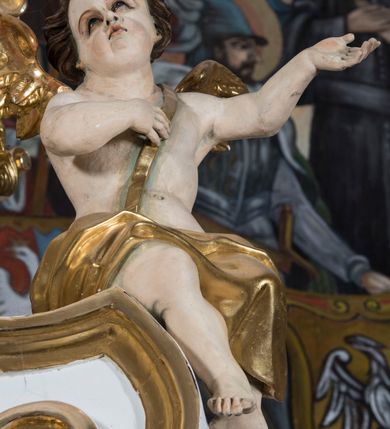 Zdjęcie nr 29: Ołtarz drewniany, prostopadłościenny. Mensa drewniana, sarkofagowa, antepedium zdobione płaskorzeźbionym kartuszem z umieszczonym w polu godłem herbu Uniwersytetu Krakowskiego na czerwonym tle.

 Nastawa architektoniczna, trójosiowa, jednokondygnacyjna ze zwieńczeniem, osadzona na dwustrefowym cokole, o osiach bocznych ustawionych ukośnie. Kondygnacja ujęta parą pilastrów oraz dwiema parami kolumn podtrzymujących przerwane belkowanie,  na którym znajduje się para puttów. W polu środkowym obraz z przedstawieniem Matki Boskiej od Odkupienia Niewolników ujęty prostokątną, profilowaną ramą zamkniętą łukiem nadwieszonym. Na cokole, po bokach obrazu ustawione dwie rzeźby: po lewej św. Kryspina, po prawej św. Kryspiniana; w osiach bocznych, w płytkich wnękach: po lewej rzeźba św. Szczepana, po prawej św. Wawrzyńca. Nad obrazem Matki Boskiej płaskorzeźbiony kartusz rocaille’owy z wpisanym w polu napisem „O / MARYO / odkupicielko / więźniów / módl się / za nami!”.

 Zwieńczenie w formie rozbudowanej aediculi, o osiach bocznych ustawionych ukośnie, z przodu flankowane dwiema wolutami z siedzącą na nich parą aniołków, zamknięte przerywanym, profilowanym gzymsem z ulokowaną na nim parą wazonów płomienistych. W polu zwieńczenia płycina wypełniona obłokami, o fantazyjnym kartuszowym wykroju z przedstawieniem Oka Opatrzności wpisanym w trójkąt na tle trzech wiązek promieni. Szczyt jest w formie promienistej glorii z parą uskrzydlonych główek anielskich.

 Kolumny złocone, ustawione na profilowanych bazach, o gładkim trzonie, kapitele w porządku kompozytowym.

 Partie cokołu zdobione prostokątnymi płycinami o wyciętych narożach.

 Struktura malowana w kolorze jasnobeżowym, ornamentyka i detale złocone i srebrzone, profilowania w kolorze czerwonym i złoconym.