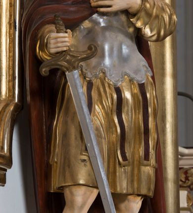 Zdjęcie nr 14: Ołtarz drewniany, prostopadłościenny. Mensa drewniana, sarkofagowa, antepedium zdobione płaskorzeźbionym kartuszem z umieszczonym w polu godłem herbu Uniwersytetu Krakowskiego na czerwonym tle.

 Nastawa architektoniczna, trójosiowa, jednokondygnacyjna ze zwieńczeniem, osadzona na dwustrefowym cokole, o osiach bocznych ustawionych ukośnie. Kondygnacja ujęta parą pilastrów oraz dwiema parami kolumn podtrzymujących przerwane belkowanie,  na którym znajduje się para puttów. W polu środkowym obraz z przedstawieniem Matki Boskiej od Odkupienia Niewolników ujęty prostokątną, profilowaną ramą zamkniętą łukiem nadwieszonym. Na cokole, po bokach obrazu ustawione dwie rzeźby: po lewej św. Kryspina, po prawej św. Kryspiniana; w osiach bocznych, w płytkich wnękach: po lewej rzeźba św. Szczepana, po prawej św. Wawrzyńca. Nad obrazem Matki Boskiej płaskorzeźbiony kartusz rocaille’owy z wpisanym w polu napisem „O / MARYO / odkupicielko / więźniów / módl się / za nami!”.

 Zwieńczenie w formie rozbudowanej aediculi, o osiach bocznych ustawionych ukośnie, z przodu flankowane dwiema wolutami z siedzącą na nich parą aniołków, zamknięte przerywanym, profilowanym gzymsem z ulokowaną na nim parą wazonów płomienistych. W polu zwieńczenia płycina wypełniona obłokami, o fantazyjnym kartuszowym wykroju z przedstawieniem Oka Opatrzności wpisanym w trójkąt na tle trzech wiązek promieni. Szczyt jest w formie promienistej glorii z parą uskrzydlonych główek anielskich.

 Kolumny złocone, ustawione na profilowanych bazach, o gładkim trzonie, kapitele w porządku kompozytowym.

 Partie cokołu zdobione prostokątnymi płycinami o wyciętych narożach.

 Struktura malowana w kolorze jasnobeżowym, ornamentyka i detale złocone i srebrzone, profilowania w kolorze czerwonym i złoconym.