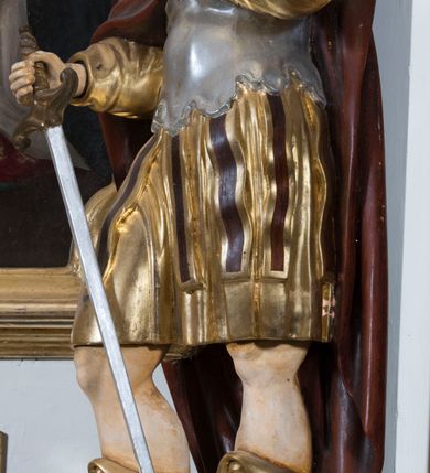 Zdjęcie nr 13: Ołtarz drewniany, prostopadłościenny. Mensa drewniana, sarkofagowa, antepedium zdobione płaskorzeźbionym kartuszem z umieszczonym w polu godłem herbu Uniwersytetu Krakowskiego na czerwonym tle.

 Nastawa architektoniczna, trójosiowa, jednokondygnacyjna ze zwieńczeniem, osadzona na dwustrefowym cokole, o osiach bocznych ustawionych ukośnie. Kondygnacja ujęta parą pilastrów oraz dwiema parami kolumn podtrzymujących przerwane belkowanie,  na którym znajduje się para puttów. W polu środkowym obraz z przedstawieniem Matki Boskiej od Odkupienia Niewolników ujęty prostokątną, profilowaną ramą zamkniętą łukiem nadwieszonym. Na cokole, po bokach obrazu ustawione dwie rzeźby: po lewej św. Kryspina, po prawej św. Kryspiniana; w osiach bocznych, w płytkich wnękach: po lewej rzeźba św. Szczepana, po prawej św. Wawrzyńca. Nad obrazem Matki Boskiej płaskorzeźbiony kartusz rocaille’owy z wpisanym w polu napisem „O / MARYO / odkupicielko / więźniów / módl się / za nami!”.

 Zwieńczenie w formie rozbudowanej aediculi, o osiach bocznych ustawionych ukośnie, z przodu flankowane dwiema wolutami z siedzącą na nich parą aniołków, zamknięte przerywanym, profilowanym gzymsem z ulokowaną na nim parą wazonów płomienistych. W polu zwieńczenia płycina wypełniona obłokami, o fantazyjnym kartuszowym wykroju z przedstawieniem Oka Opatrzności wpisanym w trójkąt na tle trzech wiązek promieni. Szczyt jest w formie promienistej glorii z parą uskrzydlonych główek anielskich.

 Kolumny złocone, ustawione na profilowanych bazach, o gładkim trzonie, kapitele w porządku kompozytowym.

 Partie cokołu zdobione prostokątnymi płycinami o wyciętych narożach.

 Struktura malowana w kolorze jasnobeżowym, ornamentyka i detale złocone i srebrzone, profilowania w kolorze czerwonym i złoconym.