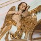 Zdjęcie nr 1: Para pełnoplastycznych, całopostaciowych figur przedstawia anioły przyklękające na przerwanym, wolutowym przyczółku zwieńczenia ołtarza. Ich zwrócone niemal w trzech czwartych, młodzieńcze sylwetki są lekko pochylone ku sobie. Owalne, szerokie twarze aniołów charakteryzują pełne, wyraziste, niemal identyczne rysy z dużymi oczami, długimi, prostymi nosami i lekko zarumienionymi policzkami. Ich falowane, brązowe, częściowo przesłaniające uszy włosy łagodnie opadają na plecy. Sylwetki aniołów, charakteryzujące się stosunkowo naturalistycznie opracowaną muskulaturą, okryte są rozwianymi, złoconymi szatami od pasa do kolan u anioła po prawej stronie i częściowo w partii bioder u anioła po lewej. Na plecach mają duże, złocone skrzydła. Anioł po lewej prawą rękę wspiera na piersiach, lewą wyciąga przed siebie, drugi obydwie składa na klatce piersiowej.      

