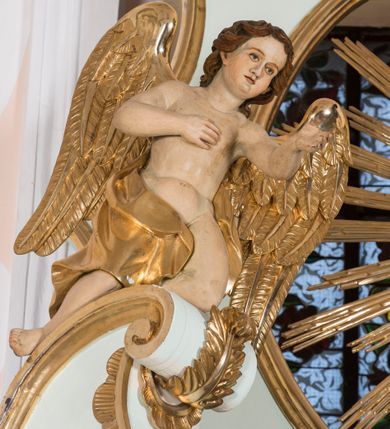 Zdjęcie nr 11: Retabulum ołtarza bocznego charakteryzuje architektoniczna, jednokondygnacyjna, jednoosiowa struktura ze zwieńczeniem. Ołtarz jest drewniany, sarkofagowy z drewnianą mensą. Retabulum osadzone jest na zdwojonym cokole. Część środkowa nastawy ujęta jest parą kolumn i dwoma parami pilastrów, z których jedna ma wklęsłe trzony. Wspomniane elementy wspierają wyłamujące się ponad nimi wklęsło-wypukłe belkowanie. Pole środkowe retabulum jest w kształcie stojącego prostokąta zamkniętego półkolistym łukiem nadwieszonym z uskokami, ujęte jest profilowaną, złoconą ramą. Zwieńczenie, w kształcie stojącego prostokąta zamknięte jest gzymsem w formie nadwieszonego łuku z uskokami. Pole środkowe stanowi owalny prześwit ujęty profilowaną, złoconą ramą. Po bokach zwieńczenia usytuowany jest przerwany, skośnie ustawiony wolutowy przyczółek. Po środku antepedium znajduje się polichromowane gorejące serce Jezusa ujęte gałązkami czerwonej róży. Pola cokołów zdobi ornamentyka rocaille’owo-akantowa. Część środkową retabulum ujmuje para ażurowych uszaków z liści akantu z motywami kogucich grzebieni. Trzony wklęsłych pilastrów w dolnej partii zdobią motywy wolut zwieńczonych liśćmi akantu. W górnej partii trzonów wszystkich pilastrów znajdują się podwieszenia w formie związanych wstążkami kompozycji kwiatowo-owocowych. Kapitele zdobione są detalami ze stylizowanych liści akantu oraz niewielkimi konsolkami z motywem palmety. Fryz dekorują motywy ornamentyki rocaille’owej. Krawędź gzymsu zwieńczenia ujęta jest rodzajem lambrekinu z pojedynczych liści o lancetowatym kształcie. W prześwit wkomponowana została promienista gloria z monogramem Jezusa pośrodku, na ciemnoczerwonym tle, ujęta wieńcem srebrzonych obłoków. W polu części środkowej retabulum znajduje się obraz Najświętsze Serce Jezusa, dodatkowo po bokach, na półkoliście wysuniętych partiach cokołu retabulum usytuowana jest para niewielkich rzeźb św. Rocha i św. Grzegorza Wielkiego. Na przerwanym przyczółku znajduje się para figur aniołów. 
Struktura retabulum utrzymana jest w pastelowym odcieniu turkusu z akcentem ciemnej czerwieni, partie detalu architektonicznego i ornamentyka są złocone i srebrzone.    
