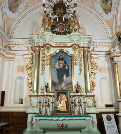 Zdjęcie nr 1: Retabulum ołtarza bocznego charakteryzuje architektoniczna, jednokondygnacyjna, jednoosiowa struktura ze zwieńczeniem. Ołtarz jest drewniany, sarkofagowy z drewnianą mensą. Retabulum osadzone jest na zdwojonym cokole. Część środkowa nastawy ujęta jest parą kolumn i dwoma parami pilastrów, z których jedna ma wklęsłe trzony. Wspomniane elementy wspierają wyłamujące się ponad nimi wklęsło-wypukłe belkowanie. Pole środkowe retabulum jest w kształcie stojącego prostokąta zamkniętego półkolistym łukiem nadwieszonym z uskokami, ujęte jest profilowaną, złoconą ramą. Zwieńczenie, w kształcie stojącego prostokąta zamknięte jest gzymsem w formie nadwieszonego łuku z uskokami. Pole środkowe stanowi owalny prześwit ujęty profilowaną, złoconą ramą. Po bokach zwieńczenia usytuowany jest przerwany, skośnie ustawiony wolutowy przyczółek. Po środku antepedium znajduje się polichromowane gorejące serce Jezusa ujęte gałązkami czerwonej róży. Pola cokołów zdobi ornamentyka rocaille’owo-akantowa. Część środkową retabulum ujmuje para ażurowych uszaków z liści akantu z motywami kogucich grzebieni. Trzony wklęsłych pilastrów w dolnej partii zdobią motywy wolut zwieńczonych liśćmi akantu. W górnej partii trzonów wszystkich pilastrów znajdują się podwieszenia w formie związanych wstążkami kompozycji kwiatowo-owocowych. Kapitele zdobione są detalami ze stylizowanych liści akantu oraz niewielkimi konsolkami z motywem palmety. Fryz dekorują motywy ornamentyki rocaille’owej. Krawędź gzymsu zwieńczenia ujęta jest rodzajem lambrekinu z pojedynczych liści o lancetowatym kształcie. W prześwit wkomponowana została promienista gloria z monogramem Jezusa pośrodku, na ciemnoczerwonym tle, ujęta wieńcem srebrzonych obłoków. W polu części środkowej retabulum znajduje się obraz Najświętsze Serce Jezusa, dodatkowo po bokach, na półkoliście wysuniętych partiach cokołu retabulum usytuowana jest para niewielkich rzeźb św. Rocha i św. Grzegorza Wielkiego. Na przerwanym przyczółku znajduje się para figur aniołów. 
Struktura retabulum utrzymana jest w pastelowym odcieniu turkusu z akcentem ciemnej czerwieni, partie detalu architektonicznego i ornamentyka są złocone i srebrzone.    
