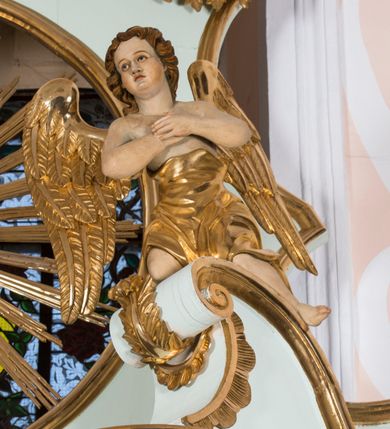 Zdjęcie nr 4: Retabulum ołtarza bocznego charakteryzuje architektoniczna, jednokondygnacyjna, jednoosiowa struktura ze zwieńczeniem. Ołtarz jest drewniany, sarkofagowy z drewnianą mensą. Retabulum osadzone jest na zdwojonym cokole. Część środkowa nastawy ujęta jest parą kolumn i dwoma parami pilastrów, z których jedna ma wklęsłe trzony. Wspomniane elementy wspierają wyłamujące się ponad nimi wklęsło-wypukłe belkowanie. Pole środkowe retabulum jest w kształcie stojącego prostokąta zamkniętego półkolistym łukiem nadwieszonym z uskokami, ujęte jest profilowaną, złoconą ramą. Zwieńczenie, w kształcie stojącego prostokąta zamknięte jest gzymsem w formie nadwieszonego łuku z uskokami. Pole środkowe stanowi owalny prześwit ujęty profilowaną, złoconą ramą. Po bokach zwieńczenia usytuowany jest przerwany, skośnie ustawiony wolutowy przyczółek. Po środku antepedium znajduje się polichromowane gorejące serce Jezusa ujęte gałązkami czerwonej róży. Pola cokołów zdobi ornamentyka rocaille’owo-akantowa. Część środkową retabulum ujmuje para ażurowych uszaków z liści akantu z motywami kogucich grzebieni. Trzony wklęsłych pilastrów w dolnej partii zdobią motywy wolut zwieńczonych liśćmi akantu. W górnej partii trzonów wszystkich pilastrów znajdują się podwieszenia w formie związanych wstążkami kompozycji kwiatowo-owocowych. Kapitele zdobione są detalami ze stylizowanych liści akantu oraz niewielkimi konsolkami z motywem palmety. Fryz dekorują motywy ornamentyki rocaille’owej. Krawędź gzymsu zwieńczenia ujęta jest rodzajem lambrekinu z pojedynczych liści o lancetowatym kształcie. W prześwit wkomponowana została promienista gloria z monogramem Jezusa pośrodku, na ciemnoczerwonym tle, ujęta wieńcem srebrzonych obłoków. W polu części środkowej retabulum znajduje się obraz Najświętsze Serce Jezusa, dodatkowo po bokach, na półkoliście wysuniętych partiach cokołu retabulum usytuowana jest para niewielkich rzeźb św. Rocha i św. Grzegorza Wielkiego. Na przerwanym przyczółku znajduje się para figur aniołów. 
Struktura retabulum utrzymana jest w pastelowym odcieniu turkusu z akcentem ciemnej czerwieni, partie detalu architektonicznego i ornamentyka są złocone i srebrzone.    
