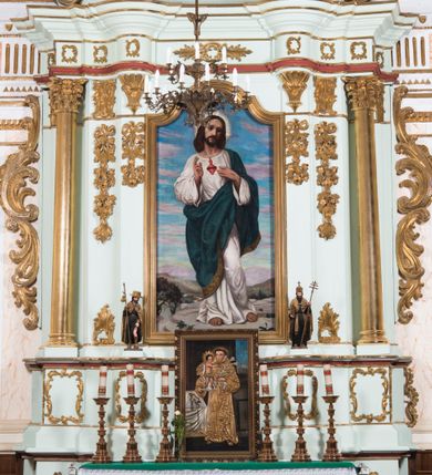 Zdjęcie nr 2: Retabulum ołtarza bocznego charakteryzuje architektoniczna, jednokondygnacyjna, jednoosiowa struktura ze zwieńczeniem. Ołtarz jest drewniany, sarkofagowy z drewnianą mensą. Retabulum osadzone jest na zdwojonym cokole. Część środkowa nastawy ujęta jest parą kolumn i dwoma parami pilastrów, z których jedna ma wklęsłe trzony. Wspomniane elementy wspierają wyłamujące się ponad nimi wklęsło-wypukłe belkowanie. Pole środkowe retabulum jest w kształcie stojącego prostokąta zamkniętego półkolistym łukiem nadwieszonym z uskokami, ujęte jest profilowaną, złoconą ramą. Zwieńczenie, w kształcie stojącego prostokąta zamknięte jest gzymsem w formie nadwieszonego łuku z uskokami. Pole środkowe stanowi owalny prześwit ujęty profilowaną, złoconą ramą. Po bokach zwieńczenia usytuowany jest przerwany, skośnie ustawiony wolutowy przyczółek. Po środku antepedium znajduje się polichromowane gorejące serce Jezusa ujęte gałązkami czerwonej róży. Pola cokołów zdobi ornamentyka rocaille’owo-akantowa. Część środkową retabulum ujmuje para ażurowych uszaków z liści akantu z motywami kogucich grzebieni. Trzony wklęsłych pilastrów w dolnej partii zdobią motywy wolut zwieńczonych liśćmi akantu. W górnej partii trzonów wszystkich pilastrów znajdują się podwieszenia w formie związanych wstążkami kompozycji kwiatowo-owocowych. Kapitele zdobione są detalami ze stylizowanych liści akantu oraz niewielkimi konsolkami z motywem palmety. Fryz dekorują motywy ornamentyki rocaille’owej. Krawędź gzymsu zwieńczenia ujęta jest rodzajem lambrekinu z pojedynczych liści o lancetowatym kształcie. W prześwit wkomponowana została promienista gloria z monogramem Jezusa pośrodku, na ciemnoczerwonym tle, ujęta wieńcem srebrzonych obłoków. W polu części środkowej retabulum znajduje się obraz Najświętsze Serce Jezusa, dodatkowo po bokach, na półkoliście wysuniętych partiach cokołu retabulum usytuowana jest para niewielkich rzeźb św. Rocha i św. Grzegorza Wielkiego. Na przerwanym przyczółku znajduje się para figur aniołów. 
Struktura retabulum utrzymana jest w pastelowym odcieniu turkusu z akcentem ciemnej czerwieni, partie detalu architektonicznego i ornamentyka są złocone i srebrzone.    
