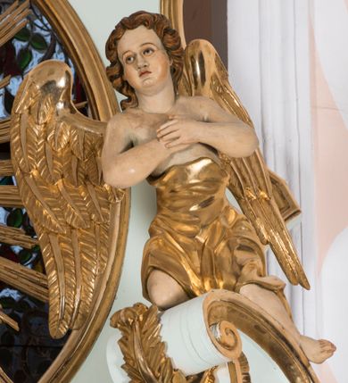 Zdjęcie nr 5: Retabulum ołtarza bocznego charakteryzuje architektoniczna, jednokondygnacyjna, jednoosiowa struktura ze zwieńczeniem. Ołtarz jest drewniany, sarkofagowy z drewnianą mensą. Retabulum osadzone jest na zdwojonym cokole. Część środkowa nastawy ujęta jest parą kolumn i dwoma parami pilastrów, z których jedna ma wklęsłe trzony. Wspomniane elementy wspierają wyłamujące się ponad nimi wklęsło-wypukłe belkowanie. Pole środkowe retabulum jest w kształcie stojącego prostokąta zamkniętego półkolistym łukiem nadwieszonym z uskokami, ujęte jest profilowaną, złoconą ramą. Zwieńczenie, w kształcie stojącego prostokąta zamknięte jest gzymsem w formie nadwieszonego łuku z uskokami. Pole środkowe stanowi owalny prześwit ujęty profilowaną, złoconą ramą. Po bokach zwieńczenia usytuowany jest przerwany, skośnie ustawiony wolutowy przyczółek. Po środku antepedium znajduje się polichromowane gorejące serce Jezusa ujęte gałązkami czerwonej róży. Pola cokołów zdobi ornamentyka rocaille’owo-akantowa. Część środkową retabulum ujmuje para ażurowych uszaków z liści akantu z motywami kogucich grzebieni. Trzony wklęsłych pilastrów w dolnej partii zdobią motywy wolut zwieńczonych liśćmi akantu. W górnej partii trzonów wszystkich pilastrów znajdują się podwieszenia w formie związanych wstążkami kompozycji kwiatowo-owocowych. Kapitele zdobione są detalami ze stylizowanych liści akantu oraz niewielkimi konsolkami z motywem palmety. Fryz dekorują motywy ornamentyki rocaille’owej. Krawędź gzymsu zwieńczenia ujęta jest rodzajem lambrekinu z pojedynczych liści o lancetowatym kształcie. W prześwit wkomponowana została promienista gloria z monogramem Jezusa pośrodku, na ciemnoczerwonym tle, ujęta wieńcem srebrzonych obłoków. W polu części środkowej retabulum znajduje się obraz Najświętsze Serce Jezusa, dodatkowo po bokach, na półkoliście wysuniętych partiach cokołu retabulum usytuowana jest para niewielkich rzeźb św. Rocha i św. Grzegorza Wielkiego. Na przerwanym przyczółku znajduje się para figur aniołów. 
Struktura retabulum utrzymana jest w pastelowym odcieniu turkusu z akcentem ciemnej czerwieni, partie detalu architektonicznego i ornamentyka są złocone i srebrzone.    
