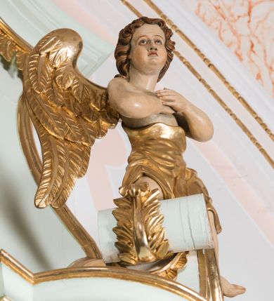 Zdjęcie nr 7: Retabulum ołtarza bocznego charakteryzuje architektoniczna, jednokondygnacyjna, jednoosiowa struktura ze zwieńczeniem. Ołtarz jest drewniany, sarkofagowy z drewnianą mensą. Retabulum osadzone jest na zdwojonym cokole. Część środkowa nastawy ujęta jest parą kolumn i dwoma parami pilastrów, z których jedna ma wklęsłe trzony. Wspomniane elementy wspierają wyłamujące się ponad nimi wklęsło-wypukłe belkowanie. Pole środkowe retabulum jest w kształcie stojącego prostokąta zamkniętego półkolistym łukiem nadwieszonym z uskokami, ujęte jest profilowaną, złoconą ramą. Zwieńczenie, w kształcie stojącego prostokąta zamknięte jest gzymsem w formie nadwieszonego łuku z uskokami. Pole środkowe stanowi owalny prześwit ujęty profilowaną, złoconą ramą. Po bokach zwieńczenia usytuowany jest przerwany, skośnie ustawiony wolutowy przyczółek. Po środku antepedium znajduje się polichromowane gorejące serce Jezusa ujęte gałązkami czerwonej róży. Pola cokołów zdobi ornamentyka rocaille’owo-akantowa. Część środkową retabulum ujmuje para ażurowych uszaków z liści akantu z motywami kogucich grzebieni. Trzony wklęsłych pilastrów w dolnej partii zdobią motywy wolut zwieńczonych liśćmi akantu. W górnej partii trzonów wszystkich pilastrów znajdują się podwieszenia w formie związanych wstążkami kompozycji kwiatowo-owocowych. Kapitele zdobione są detalami ze stylizowanych liści akantu oraz niewielkimi konsolkami z motywem palmety. Fryz dekorują motywy ornamentyki rocaille’owej. Krawędź gzymsu zwieńczenia ujęta jest rodzajem lambrekinu z pojedynczych liści o lancetowatym kształcie. W prześwit wkomponowana została promienista gloria z monogramem Jezusa pośrodku, na ciemnoczerwonym tle, ujęta wieńcem srebrzonych obłoków. W polu części środkowej retabulum znajduje się obraz Najświętsze Serce Jezusa, dodatkowo po bokach, na półkoliście wysuniętych partiach cokołu retabulum usytuowana jest para niewielkich rzeźb św. Rocha i św. Grzegorza Wielkiego. Na przerwanym przyczółku znajduje się para figur aniołów. 
Struktura retabulum utrzymana jest w pastelowym odcieniu turkusu z akcentem ciemnej czerwieni, partie detalu architektonicznego i ornamentyka są złocone i srebrzone.    
