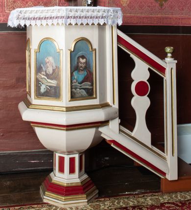 Zdjęcie nr 1: Ambona przyścienna, stojąca, z dostępem z prawej strony w postaci jednobiegowych schodów z podestem i balustradą. Kosz wsparty jest na ośmiobocznej, uskokowo profilowanej stopie, a następnie na o ośmiobocznym trzonie dekorowanym płycinami w kształcie pionowych prostokątów.

Kosz jest także na rzucie ośmioboku, z wydatną listwą cokołową u nasady, posiadającą formę masywnego wałka i profilowanym gzymsem w partii zwieńczenia. Ścianki kosza wypełnione są płycinami w kształcie pionowych prostokątów zamkniętych półkolistymi łukami nadwieszonymi, z malowanymi przedstawieniami, od lewej: św. Jana Ewangelisty, Jezusa Dobrego Pasterza, św. Łukasza Ewangelisty oraz św. Mateusza Ewangelisty. Wszystkie osoby przedstawione są w półpostaci, ewangeliści ukazani jako piszący w księgach, z atrybutami w narożach obrazów: św. Jan z orłem, św. Łukasz z wołem oraz św. Mateusz z aniołem.

 Baldachim powtarza rzut kosza ambony, o krawędzi zdobionej lambrekinem; wyżej jest zredukowane belkowanie.

 Balustrada schodów jest z jedną, sylwetowo wyciętą, dwulalkową tralką z płaskim nodusem.

 Struktura malowana jest w kolorze jasnobeżowym, detale w kolorze czerwonym, profilowania złocone.