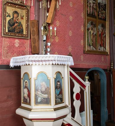 Zdjęcie nr 2: Ambona przyścienna, stojąca, z dostępem z prawej strony w postaci jednobiegowych schodów z podestem i balustradą. Kosz wsparty jest na ośmiobocznej, uskokowo profilowanej stopie, a następnie na o ośmiobocznym trzonie dekorowanym płycinami w kształcie pionowych prostokątów.

Kosz jest także na rzucie ośmioboku, z wydatną listwą cokołową u nasady, posiadającą formę masywnego wałka i profilowanym gzymsem w partii zwieńczenia. Ścianki kosza wypełnione są płycinami w kształcie pionowych prostokątów zamkniętych półkolistymi łukami nadwieszonymi, z malowanymi przedstawieniami, od lewej: św. Jana Ewangelisty, Jezusa Dobrego Pasterza, św. Łukasza Ewangelisty oraz św. Mateusza Ewangelisty. Wszystkie osoby przedstawione są w półpostaci, ewangeliści ukazani jako piszący w księgach, z atrybutami w narożach obrazów: św. Jan z orłem, św. Łukasz z wołem oraz św. Mateusz z aniołem.

 Baldachim powtarza rzut kosza ambony, o krawędzi zdobionej lambrekinem; wyżej jest zredukowane belkowanie.

 Balustrada schodów jest z jedną, sylwetowo wyciętą, dwulalkową tralką z płaskim nodusem.

 Struktura malowana jest w kolorze jasnobeżowym, detale w kolorze czerwonym, profilowania złocone.