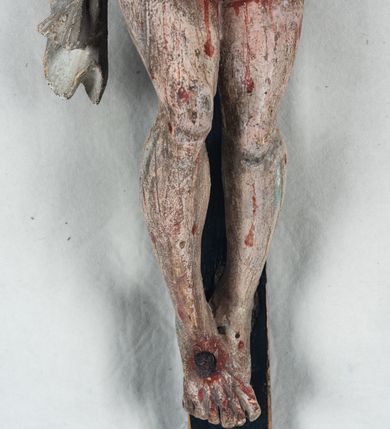 Zdjęcie nr 9: Do prostego krzyża przybita trzema gwoźdźmi pełnoplastyczna figura Chrystusa umarłego. Ciało w lekkim zwisie, o szeroko rozłożonych ramionach, głowa opadająca na prawy bark, nogi delikatnie ugięte w kolanach, stopy w układzie prawa na lewą. Chrystus ma podłużną twarz, z zamkniętymi oczami, długim, spiczastym nosem i wąskimi ustami, okoloną krótką, kręconą brodą. Włosy długie, ciemnobrązowe, silnie skręcone w pukle, opadające na plecy i prawe ramię. Na głowie szeroka korona cierniowa. Ciało szczupłe, o wyraźnie podkreślonej talii i szerokich biodrach, z delikatnie zaznaczoną muskulaturą i żebrami. Perizonium krótkie, odsłaniające prawe udo, zawiązane na prawym biodrze z opadającym wzdłuż nogi zwisem tkaniny. Polichromia ciała naturalistyczna, z zaznaczonymi śladami męki. Na zakończeniu pionowej belki krzyża kartusz z napisem „INRI”.
 
