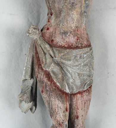 Zdjęcie nr 7: Do prostego krzyża przybita trzema gwoźdźmi pełnoplastyczna figura Chrystusa umarłego. Ciało w lekkim zwisie, o szeroko rozłożonych ramionach, głowa opadająca na prawy bark, nogi delikatnie ugięte w kolanach, stopy w układzie prawa na lewą. Chrystus ma podłużną twarz, z zamkniętymi oczami, długim, spiczastym nosem i wąskimi ustami, okoloną krótką, kręconą brodą. Włosy długie, ciemnobrązowe, silnie skręcone w pukle, opadające na plecy i prawe ramię. Na głowie szeroka korona cierniowa. Ciało szczupłe, o wyraźnie podkreślonej talii i szerokich biodrach, z delikatnie zaznaczoną muskulaturą i żebrami. Perizonium krótkie, odsłaniające prawe udo, zawiązane na prawym biodrze z opadającym wzdłuż nogi zwisem tkaniny. Polichromia ciała naturalistyczna, z zaznaczonymi śladami męki. Na zakończeniu pionowej belki krzyża kartusz z napisem „INRI”.
 
