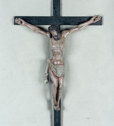 Zdjęcie nr 2: Do prostego krzyża przybita trzema gwoźdźmi pełnoplastyczna figura Chrystusa umarłego. Ciało w lekkim zwisie, o szeroko rozłożonych ramionach, głowa opadająca na prawy bark, nogi delikatnie ugięte w kolanach, stopy w układzie prawa na lewą. Chrystus ma podłużną twarz, z zamkniętymi oczami, długim, spiczastym nosem i wąskimi ustami, okoloną krótką, kręconą brodą. Włosy długie, ciemnobrązowe, silnie skręcone w pukle, opadające na plecy i prawe ramię. Na głowie szeroka korona cierniowa. Ciało szczupłe, o wyraźnie podkreślonej talii i szerokich biodrach, z delikatnie zaznaczoną muskulaturą i żebrami. Perizonium krótkie, odsłaniające prawe udo, zawiązane na prawym biodrze z opadającym wzdłuż nogi zwisem tkaniny. Polichromia ciała naturalistyczna, z zaznaczonymi śladami męki. Na zakończeniu pionowej belki krzyża kartusz z napisem „INRI”.
 
