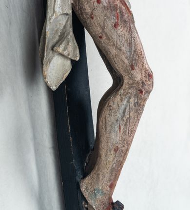 Zdjęcie nr 10: Do prostego krzyża przybita trzema gwoźdźmi pełnoplastyczna figura Chrystusa umarłego. Ciało w lekkim zwisie, o szeroko rozłożonych ramionach, głowa opadająca na prawy bark, nogi delikatnie ugięte w kolanach, stopy w układzie prawa na lewą. Chrystus ma podłużną twarz, z zamkniętymi oczami, długim, spiczastym nosem i wąskimi ustami, okoloną krótką, kręconą brodą. Włosy długie, ciemnobrązowe, silnie skręcone w pukle, opadające na plecy i prawe ramię. Na głowie szeroka korona cierniowa. Ciało szczupłe, o wyraźnie podkreślonej talii i szerokich biodrach, z delikatnie zaznaczoną muskulaturą i żebrami. Perizonium krótkie, odsłaniające prawe udo, zawiązane na prawym biodrze z opadającym wzdłuż nogi zwisem tkaniny. Polichromia ciała naturalistyczna, z zaznaczonymi śladami męki. Na zakończeniu pionowej belki krzyża kartusz z napisem „INRI”.
 
