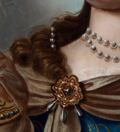 Zdjęcie nr 7: Obraz ze św. Barbarą ma kształt pionowego prostokąta zbliżonego do kwadratu. Ujmuje go drewniana rama dekorowana ornamentem roślinnym w narożach oraz geometrycznym na środku każdej z listew. Święta została przedstawiona w dwóch trzecich w ujęciu trzy czwarte w prawo na jasnobrązowym tle. Męczenniczka w charakterystycznie obróconej prawej ręce trzyma uniesiony na wysokości piersi złoty kielich z jaśniejącą hostią, zdobioną chrystogramem „IHS”. Z kolei w lewej ręce, nieznacznie wyprostowanej, ma miecz ze złotą rękojeścią. Barbara ma nieznacznie uniesioną głowę z pociągłą, owalną twarzą o jasnej karnacji z rumianymi policzkami. Charakteryzuje ją wysokie czoło, łagodna delta nosowa z prostym nosem, brązowe oczy i wąskie usta. Głowę otaczają falujące, brązowe włosy, opadające lokami na ramiona i odsłaniające fragment lewego ucha. We włosy wpleciony został sznur pereł wychodzący od owalnego, złotego, kameryzowanego klejnotu widocznego nad czołem poniżej korony. Złota korona posiada kameryzowaną obręcz oraz dziewięć ostro zakończonych sterczyn zwieńczonych perłą. Na szyi świętej znajduje się podwójny sznur pereł. Podłużna perła oprawiana w złoto widoczna jest także w jej uchu. Głowę otacza świetlisto-promienisty nimb. Święta Barbara ubrana jest w błękitną, mocno taliowaną suknię z dekoltem, odsłaniającą koronkowe, białe rękawy spodniej koszuli. Suknię dekoruje delikatny, złoty ornament roślinny. Męczenniczka ma na ramionach narzucony purpurowy płaszcz podbity zielenią, lamowany złotą taśmą. Wokół jej szyi widoczna jest jasnobrązowa chusta narzucona na płaszcz, spięta na piersiach i lewym ramieniu złotymi, owalnymi klejnotami. Klejnot na piersi dodatkowo zdobiony jest wiszącymi trzema podłużnymi perłami. Za św. Barbarą z lewej strony widoczna jest jasnobrązowa, dwupoziomowa, cylindryczna wieża z wyraźnie zaznaczonym wątkiem muru oraz fryzem koronującym, nakryta czerwonym dachem. Budowla posiada dwa nierównomiernie rozmieszczone owalne okna z kratą.  