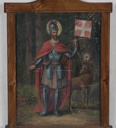 Zdjęcie nr 2: Obraz ujęty prostą, modrzewiową, lakierowaną ramą uzyskał kształt stojącego prostokąta. W centrum w całej postaci przedstawiono stojącego frontalnie na tle lasu św. Huberta. Głowę świętego ukazano w ujęciu trzy czwarte w lewo. W lewej ręce trzyma drewnianą lancę zakończoną stalowym grotem z czerwonym proporcem zdobionym białym krzyżem równoramiennym, prawą natomiast ma odsuniętą w bok. Święty Hubert ma pociągłą twarz o jasnej karnacji i rumianych policzkach, okoloną rudawobrązowym zarostem z charakterystycznie modelowanymi wąsami. Twarz charakteryzuje prosty nos, wydatne usta oraz brązowe oczy. Na głowie ma rzymski hełm z bladofioletowym pióropuszem. Ubrany jest w rycerską pełną zbroję płytową z fartuchem, spod którego widoczna jest bladoczerwona tunika lamowana u spodu złotą taśmą. U złocistego pasa wisi miecz oraz myśliwski róg. Na ramionach ma narzucony purpurowy płaszcz sięgający ziemi, spięty na piersi. Za świętym z jego lewej strony wyłania się rudobrązowy jeleń z głową ujętą w trzech czwartych w prawo. Pomiędzy jego porożami jaśnieje krucyfiks. Tło dla postaci stanowią widoczne pnie drzew iglastych, skaliste wzniesienie porosłe trawą oraz leśne runo. 