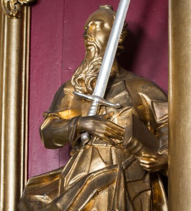 Zdjęcie nr 1: Rzeźba ścięta z tyłu i drążona, ustawiona na niskiej podstawie. 
Święty zwrócony w trzech czwartych w prawo, w kontrapoście. Lewą ręką przyciska do boku księgę, prawą kładzie na piersi i przytrzymuje miecz skierowany ostrzem w górę. Twarz ma pociągłą z wysokim czołem, o okrągłych, wyłupiastych oczach, garbatym nosie i pełnych, rozchylonych ustach; okoloną długą, rozdwajającą się brodą, opadającą na pierś oraz krótkimi, kręconymi włosami. Święty ubrany jest w tunikę ściśle przylegającą do ciała, przepasaną w talii, ostro łamaną oraz płaszcz wywinięty na prawym boku postaci, podwieszony nad lewym udem. Figura w całości złocona, miecz srebrzony. 